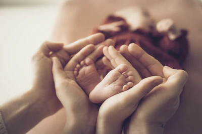 Parent's hands gently holding newborn baby's feet