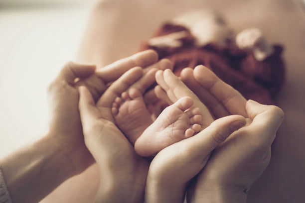 Parent's hands gently holding newborn baby's feet