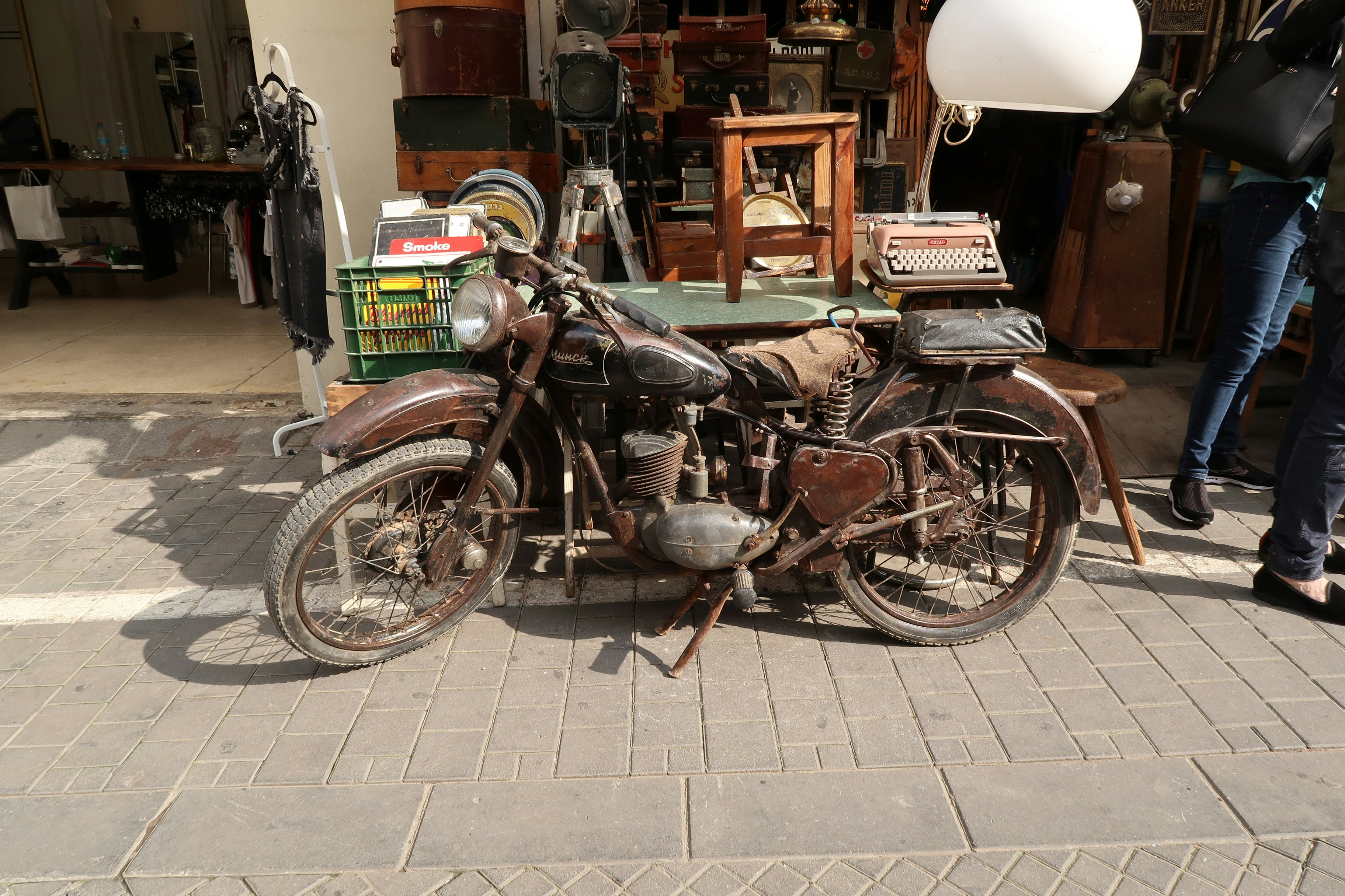 Antique motorcycle parked outside a shop with vintage items