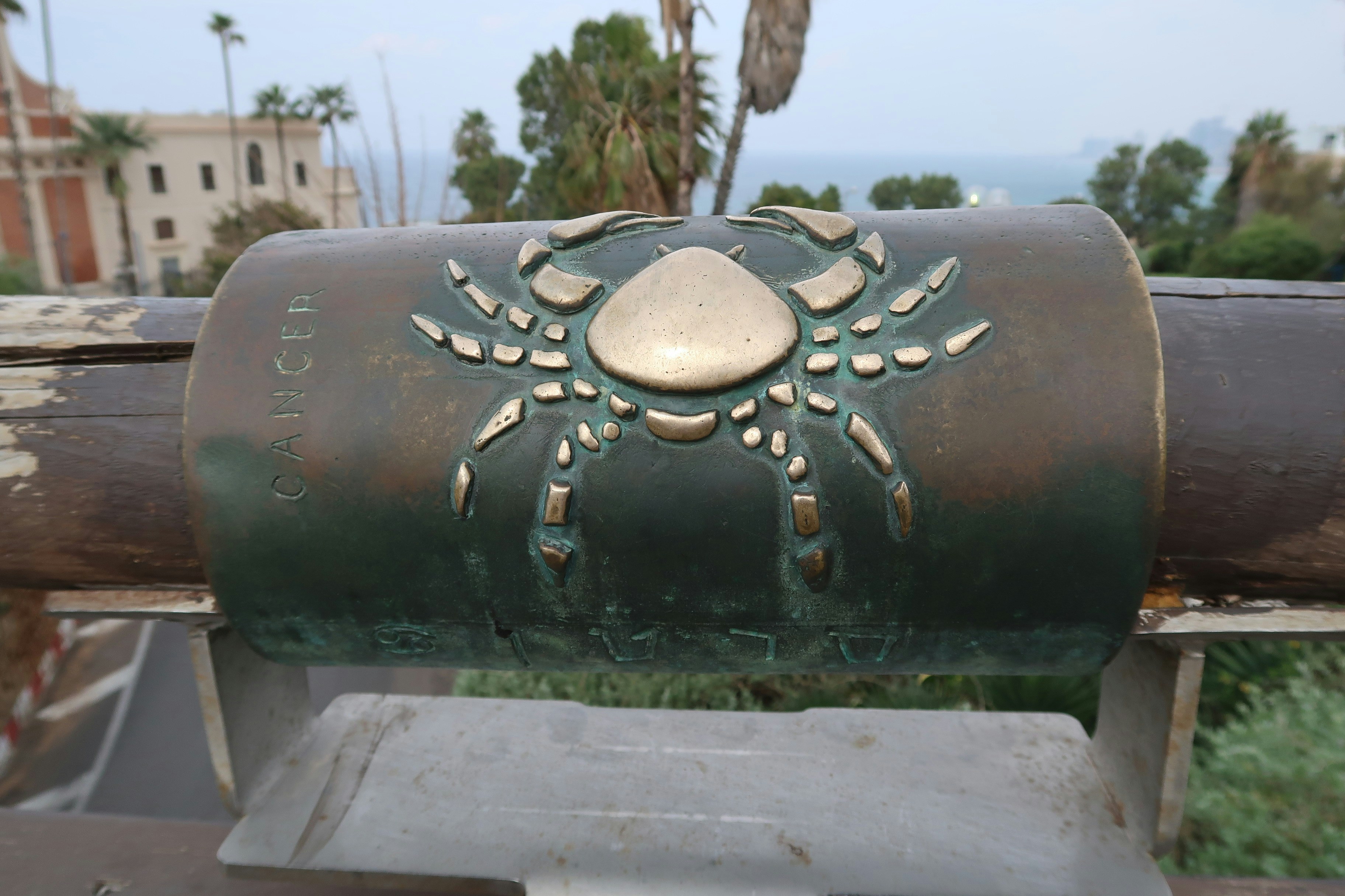 Bronze crab emblem on a cylindrical monument.