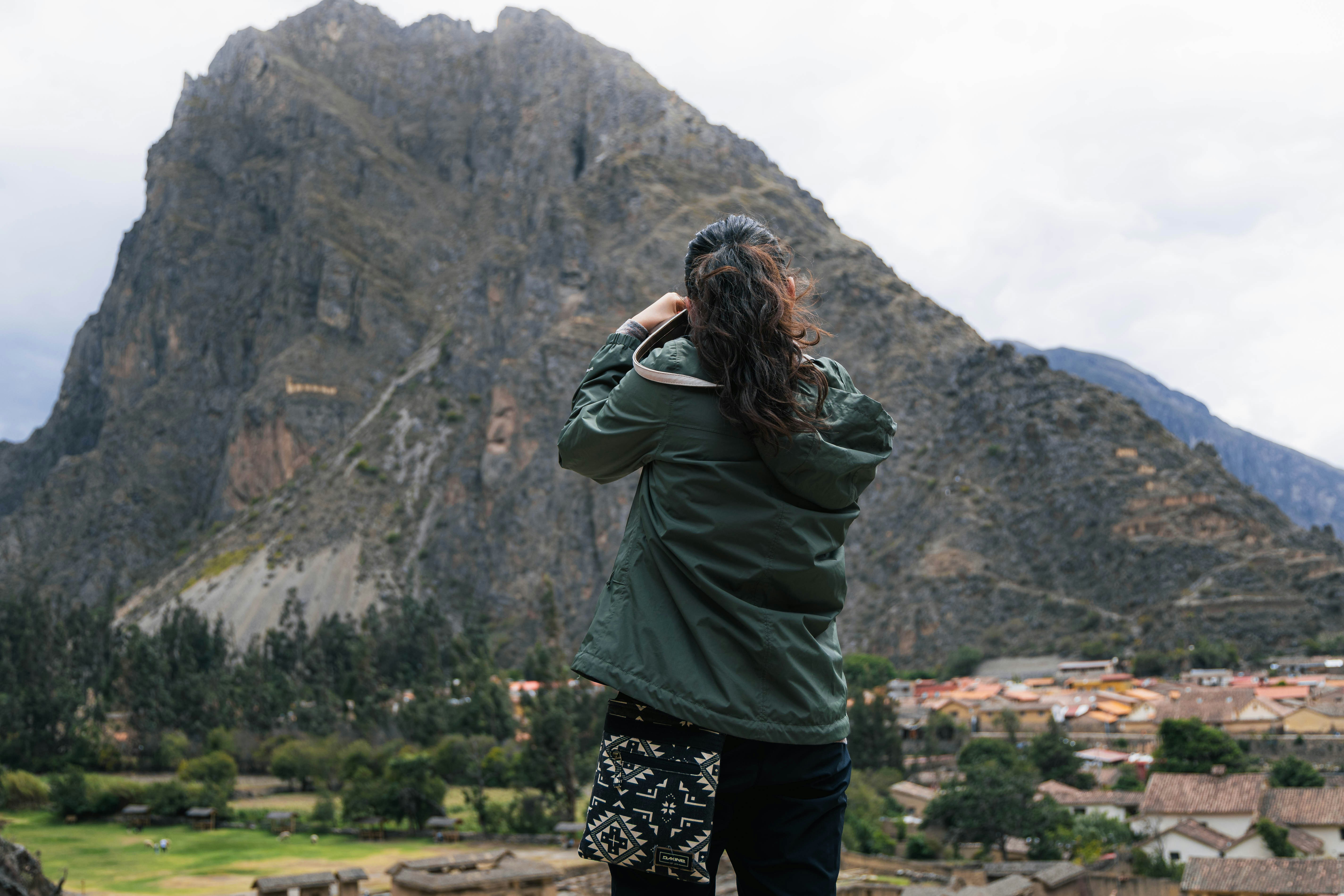 Woman photographing a large mountain and village.