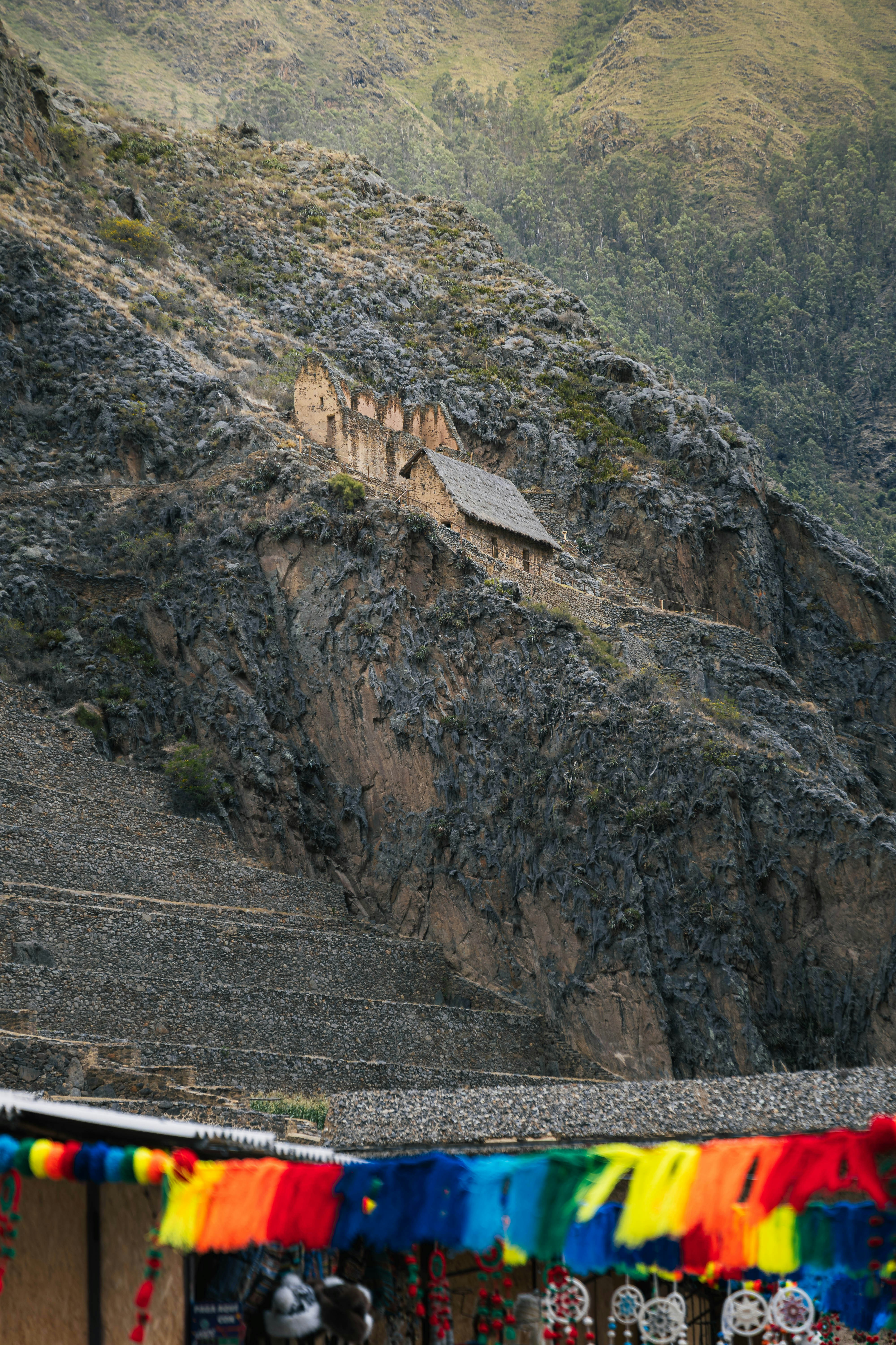 Ancient ruins built into a rocky mountainside with colorful flags.