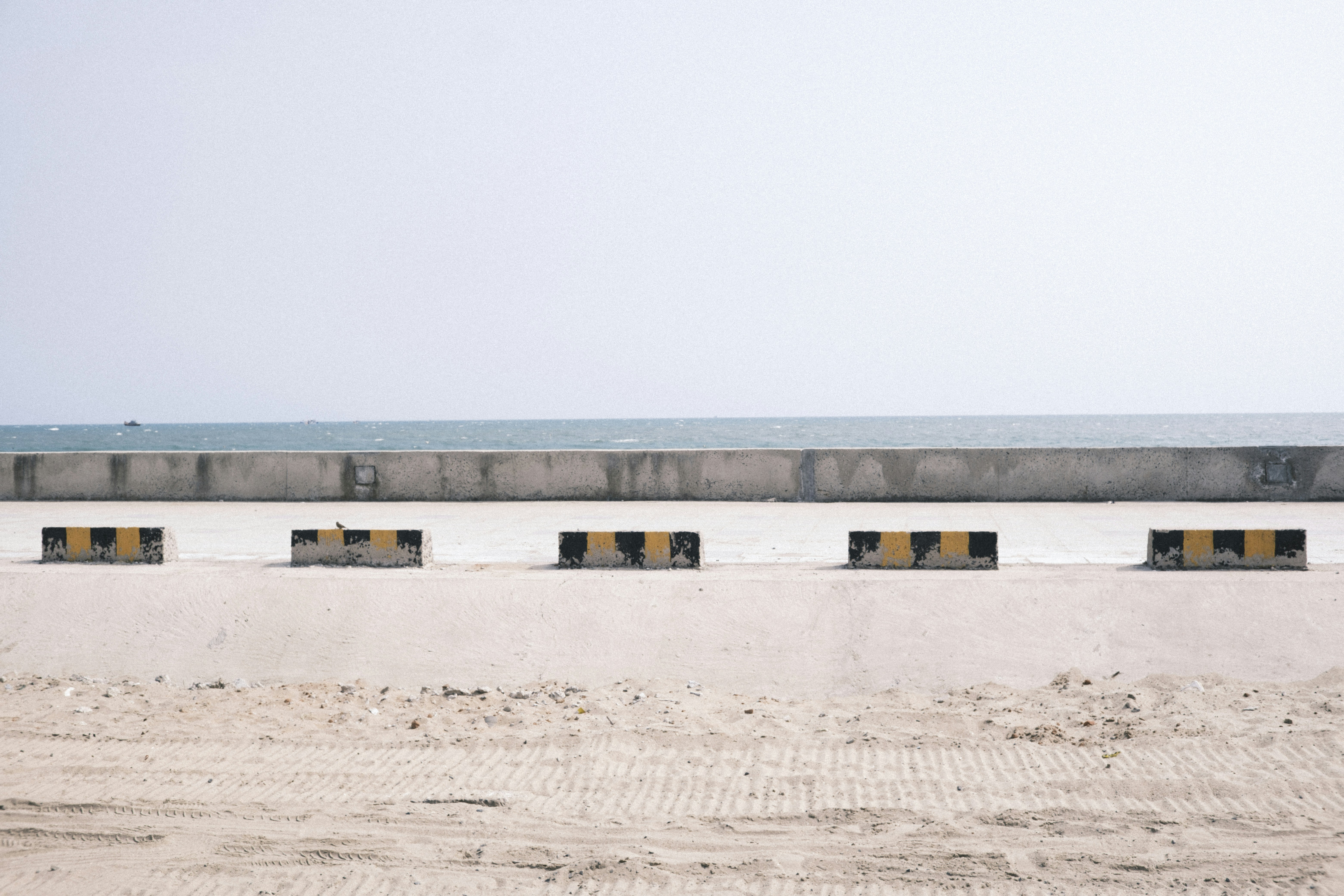 Concrete barrier and yellow striped blocks on beach