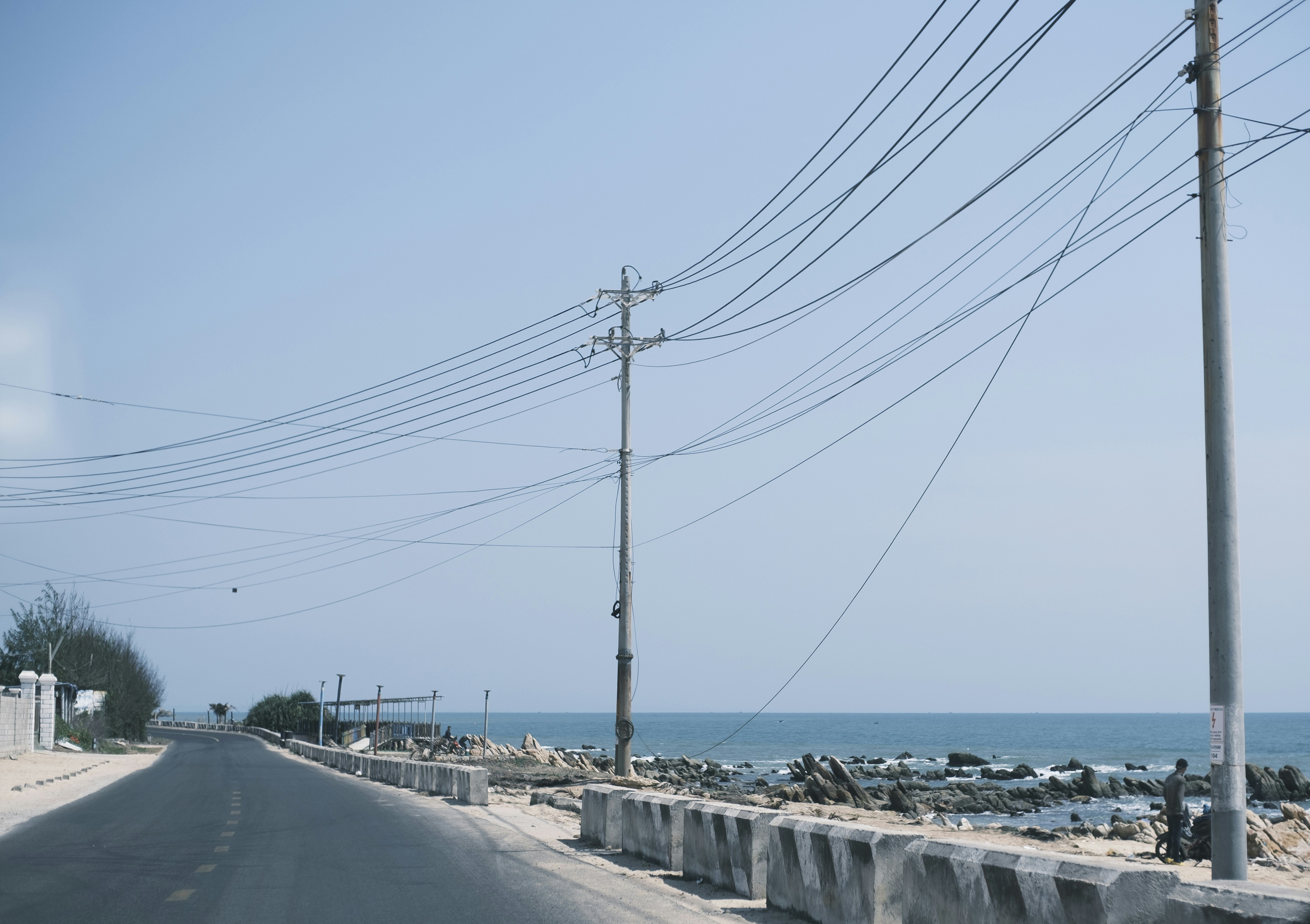Road alongside the ocean with power lines