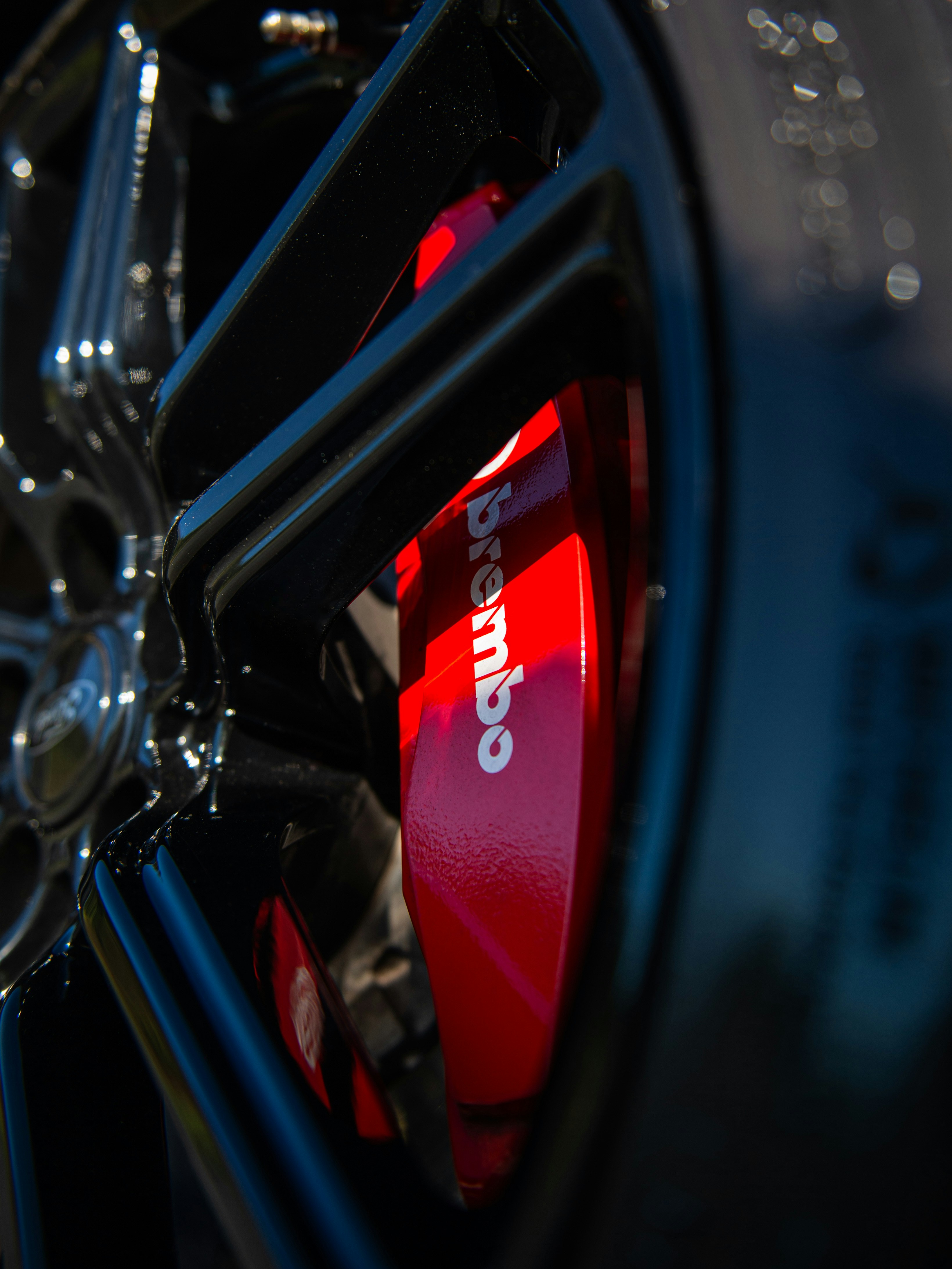 Close-up of a red brembo brake caliper on a car.
