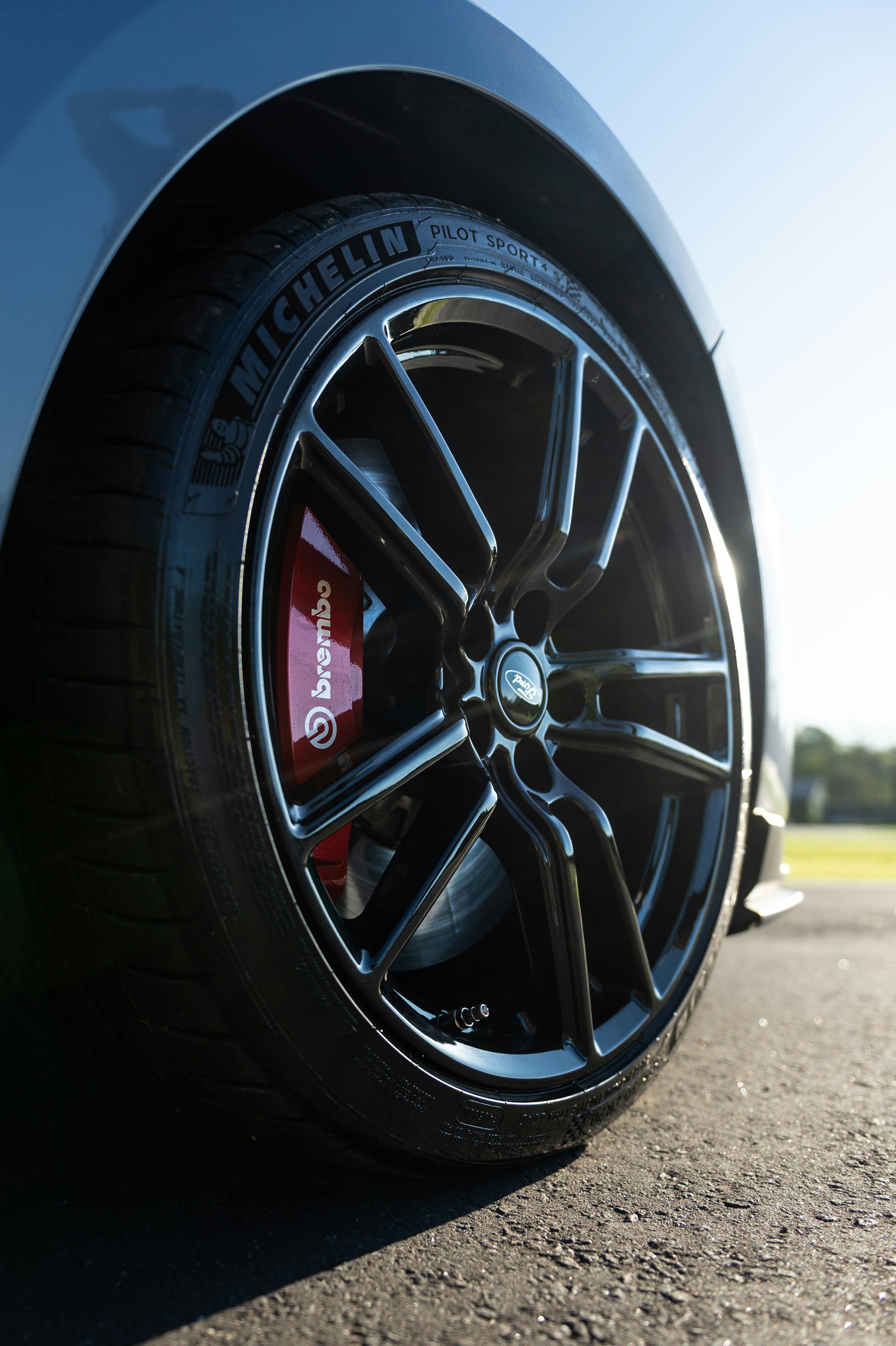 Close-up of a black car wheel with red brake caliper.