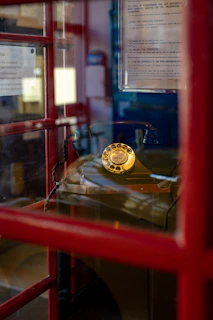 Vintage rotary dial telephone inside a red booth.