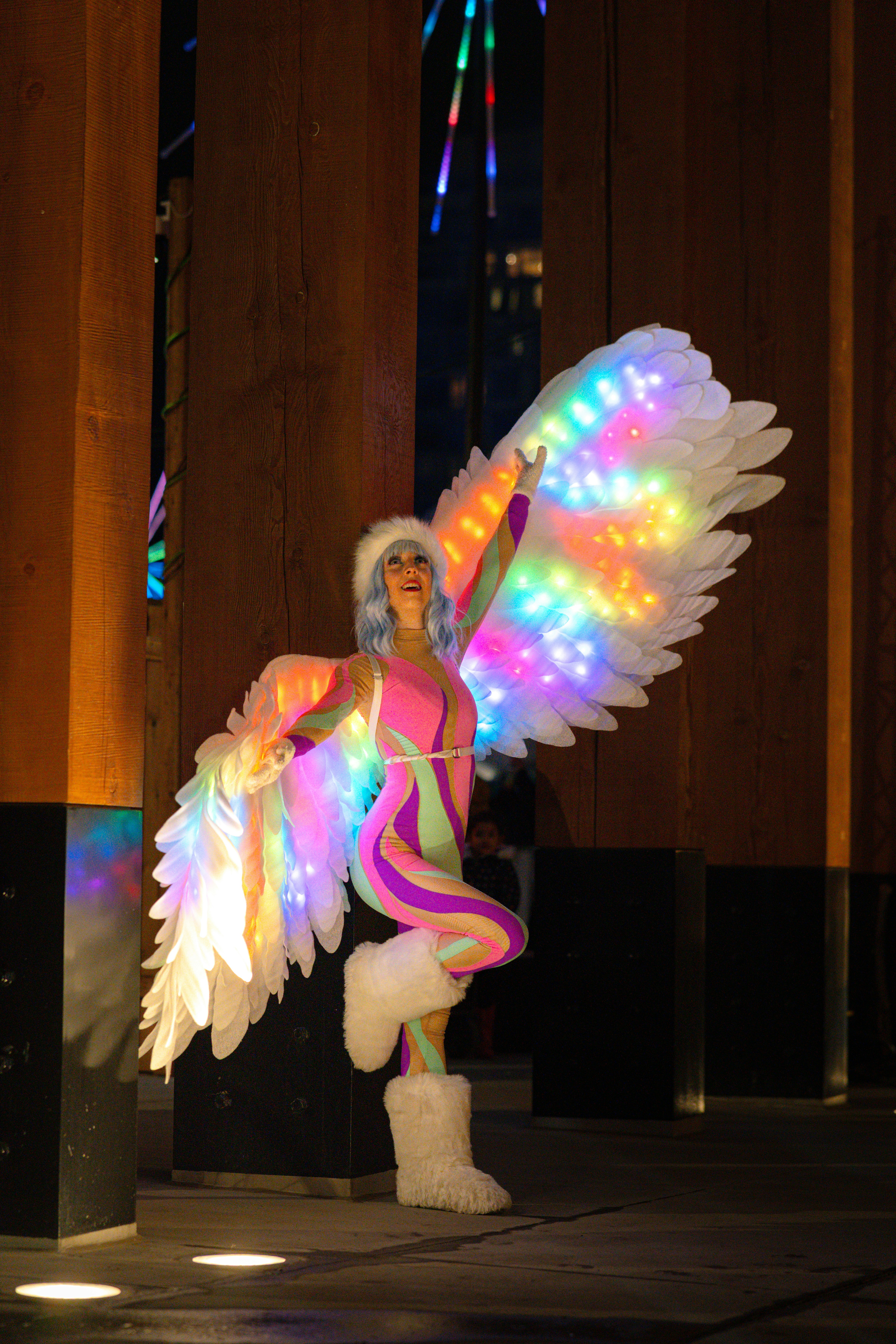 Performer in colorful costume with illuminated wings