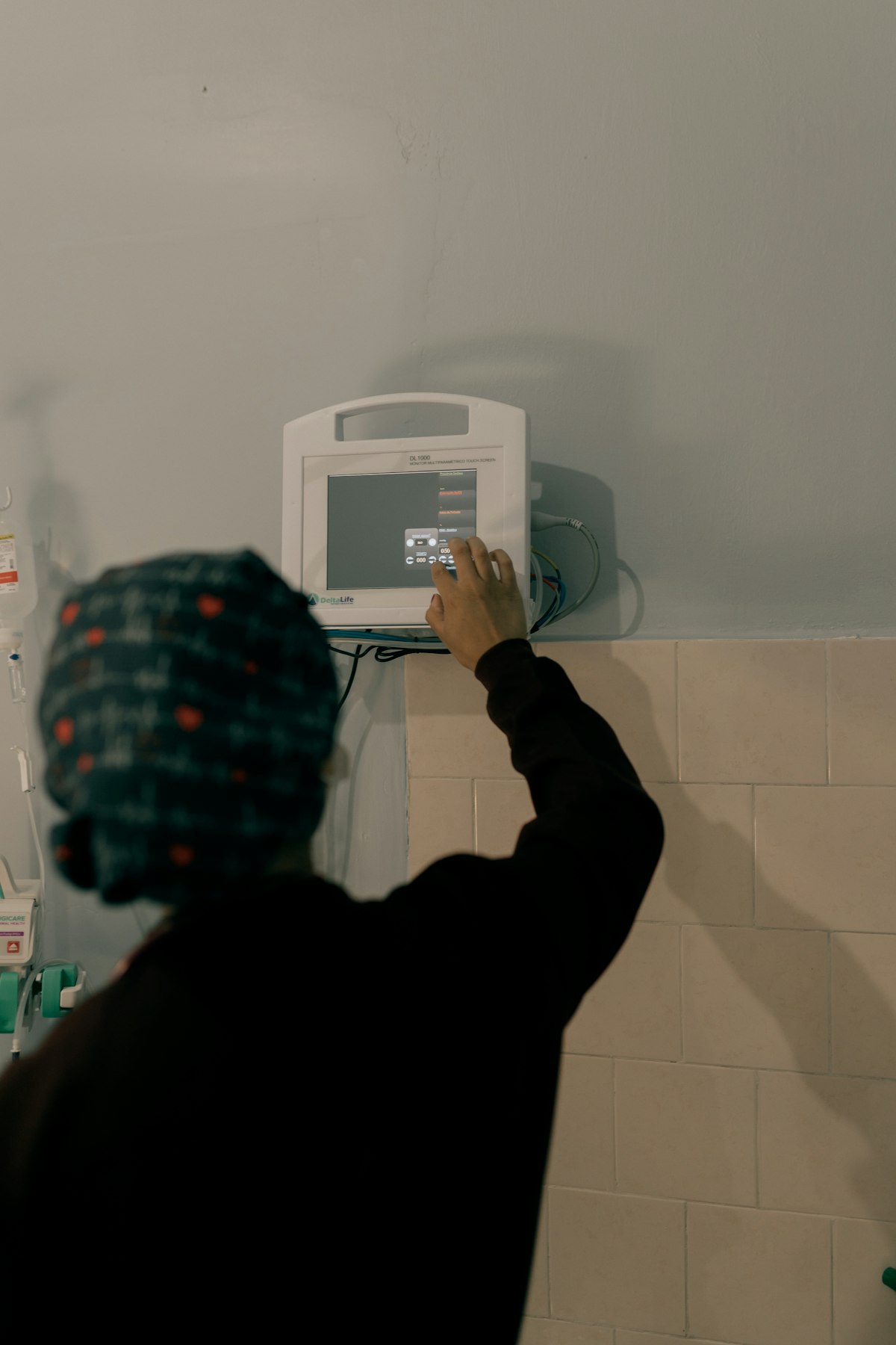 Nurse adjusting a bedside monitor supported by AI clinical decision support software in a hospital