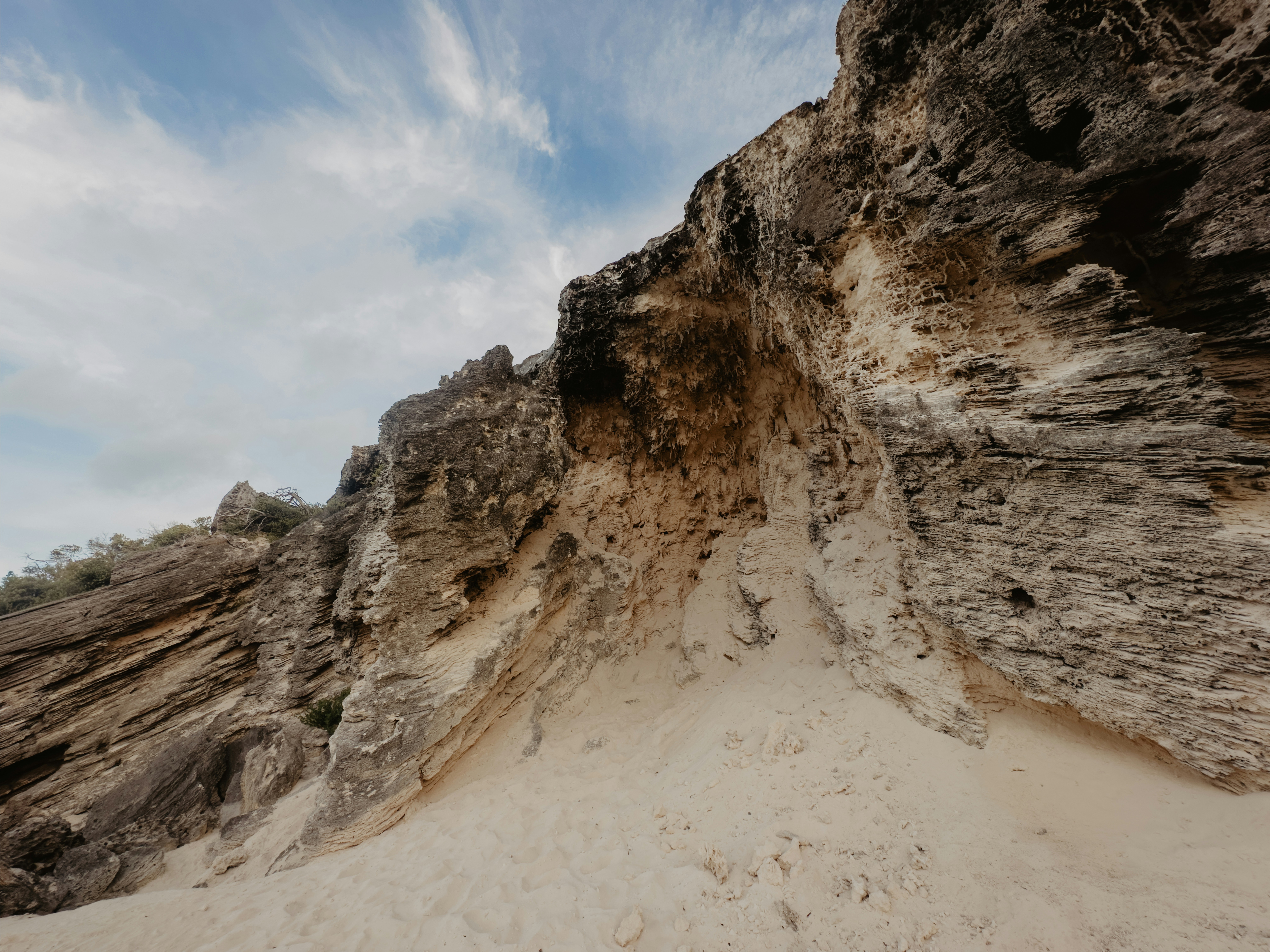 Sandy cliff face with layered rock formations under sky