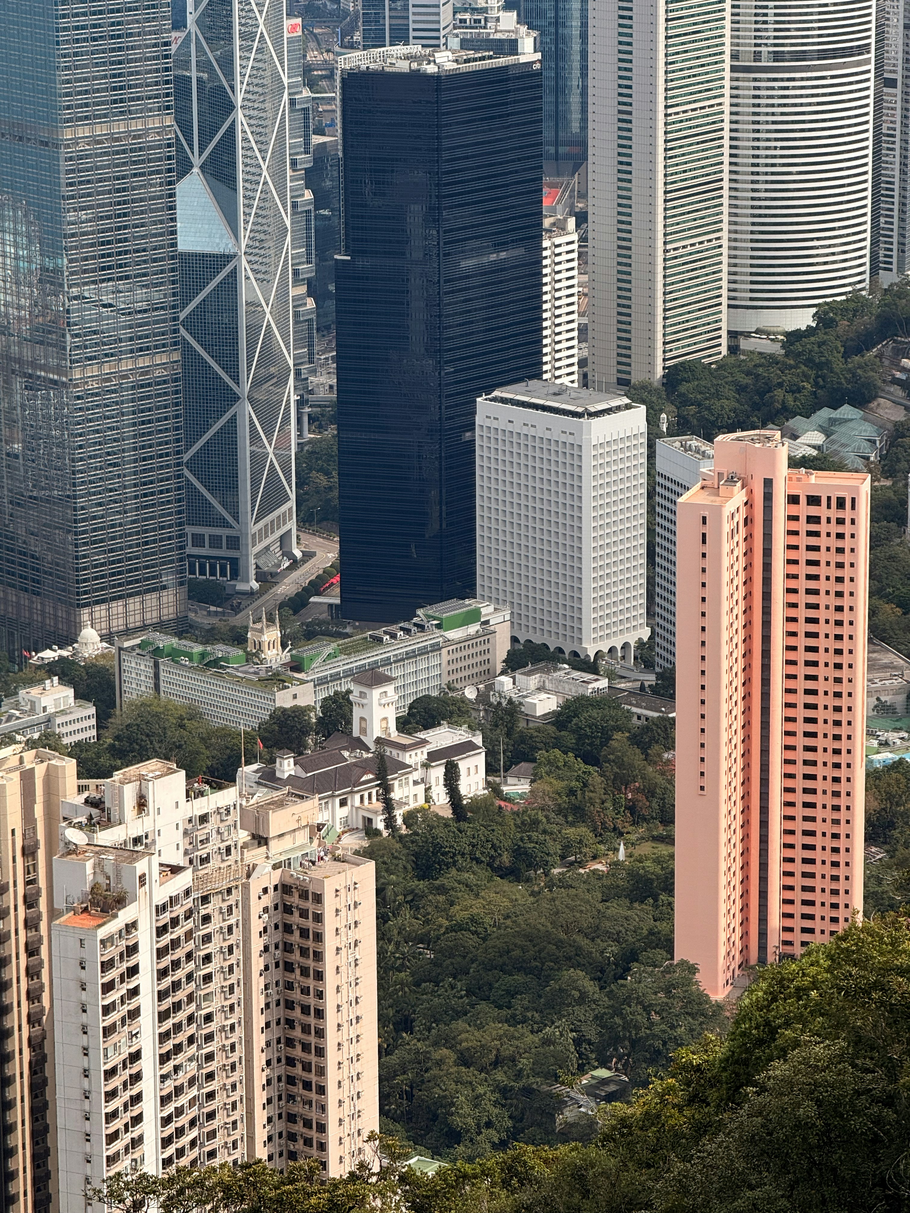 Modern skyscrapers rise above lush green trees and buildings.