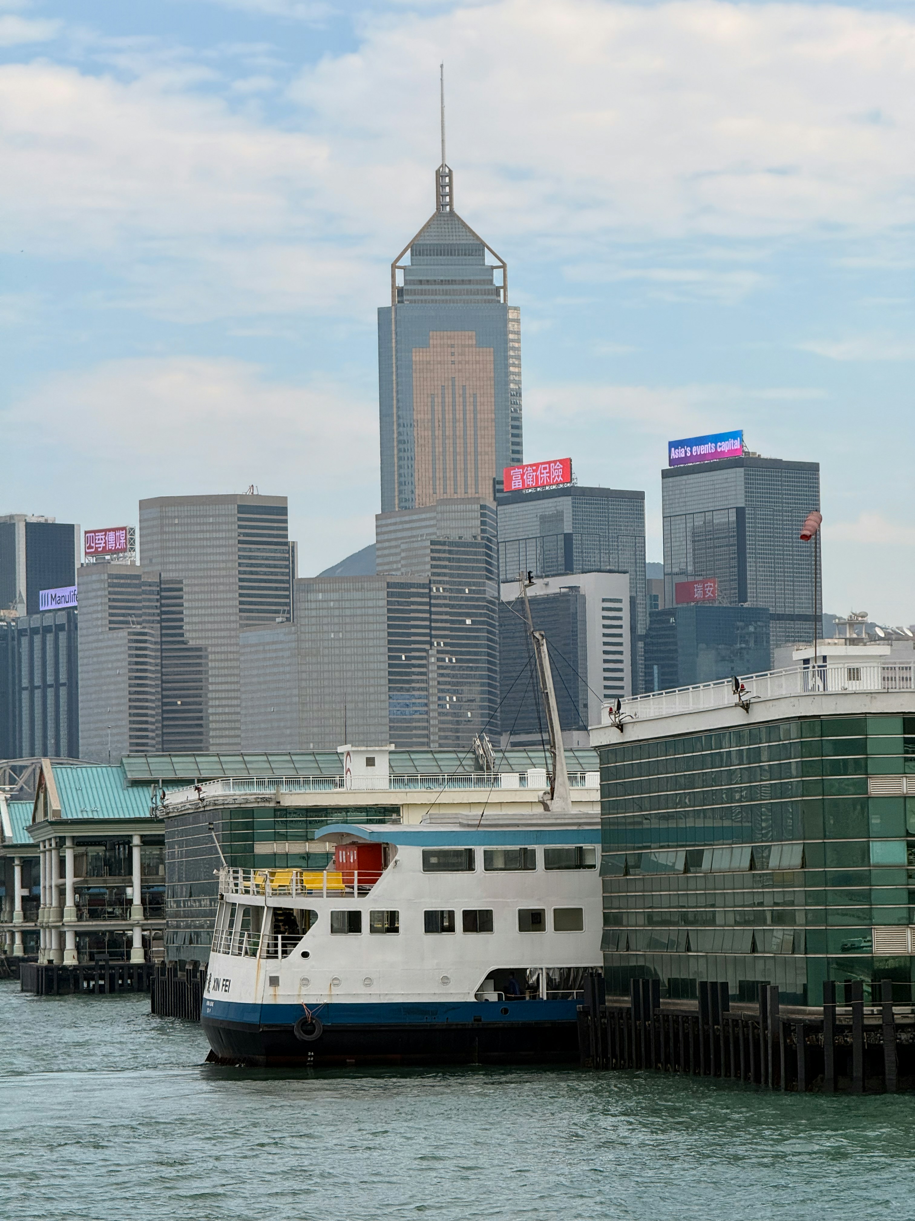 Ferry docked at pier with hong kong skyline behind