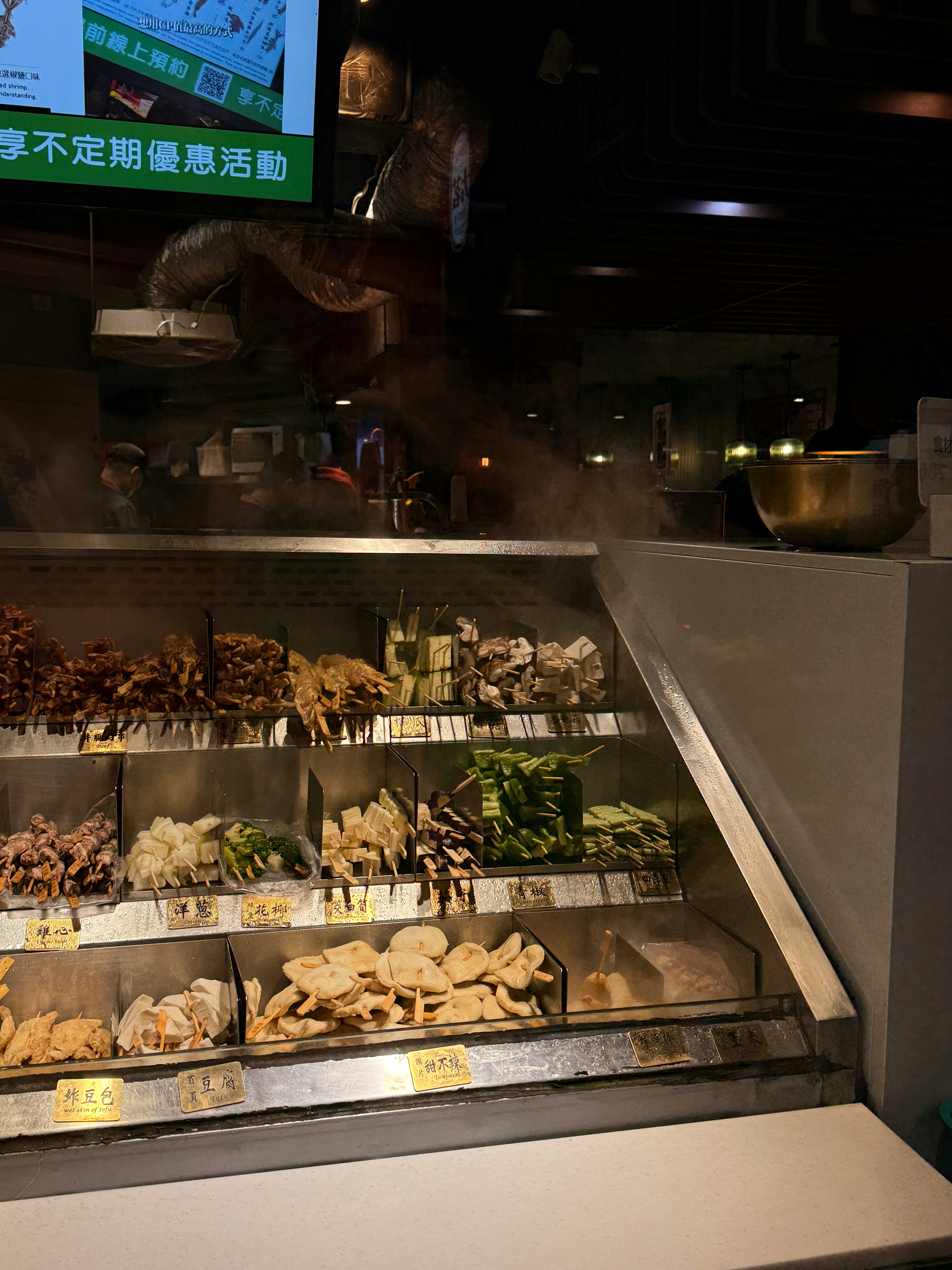 Un assortiment de brochettes de nourriture exposées dans une vitrine réfrigérée.