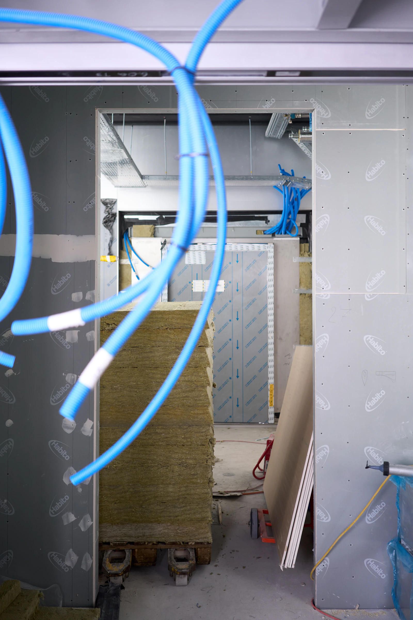 Ducting and insulation on a construction site. In a Passive House, the mechanical ventilation system — not gaps in the envelope — is what supplies fresh air on a continuous schedule.