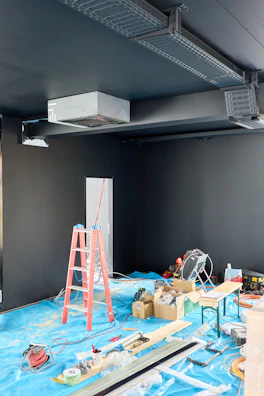 Interior construction site with tools and ladders.