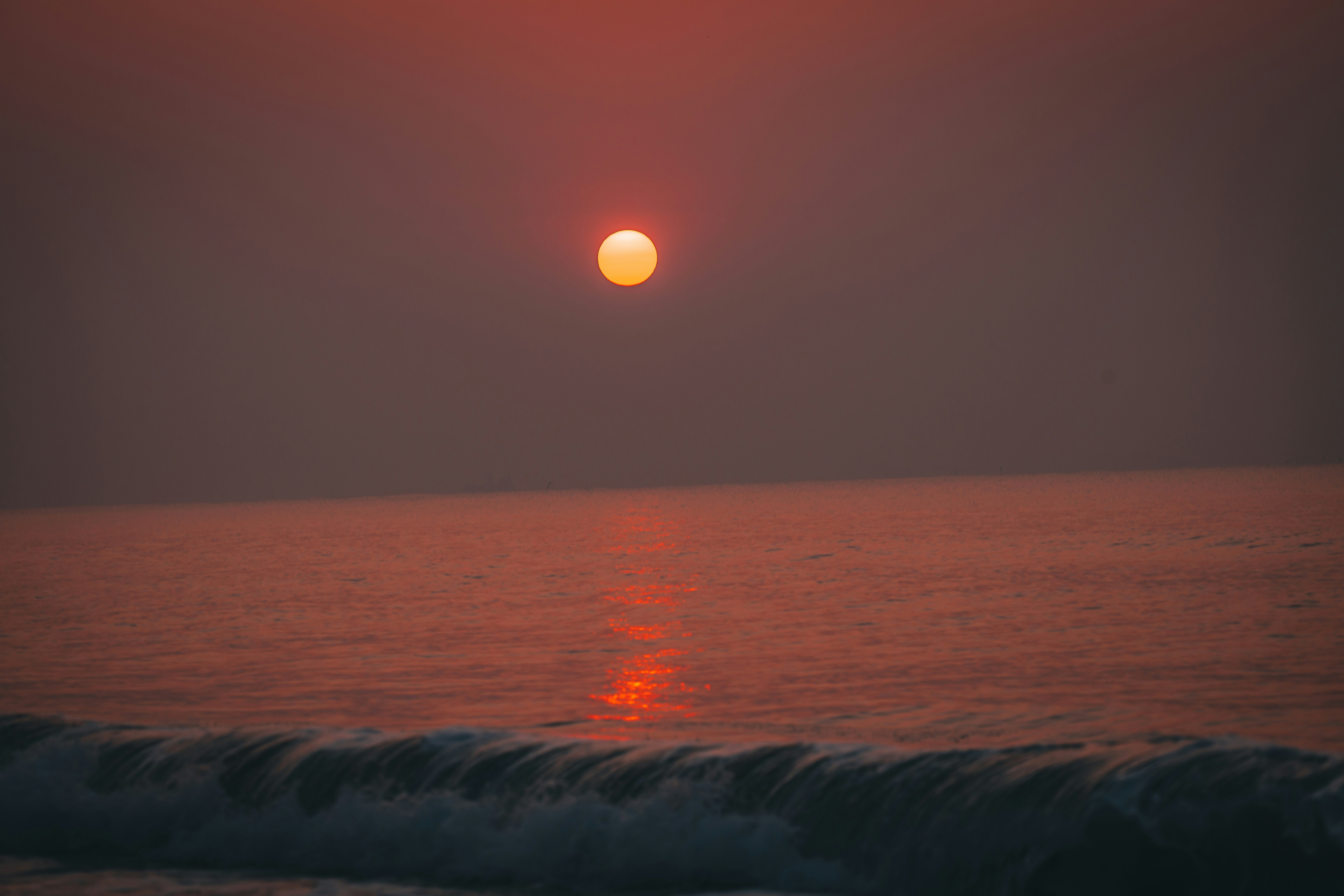 Sun setting over a calm ocean with waves