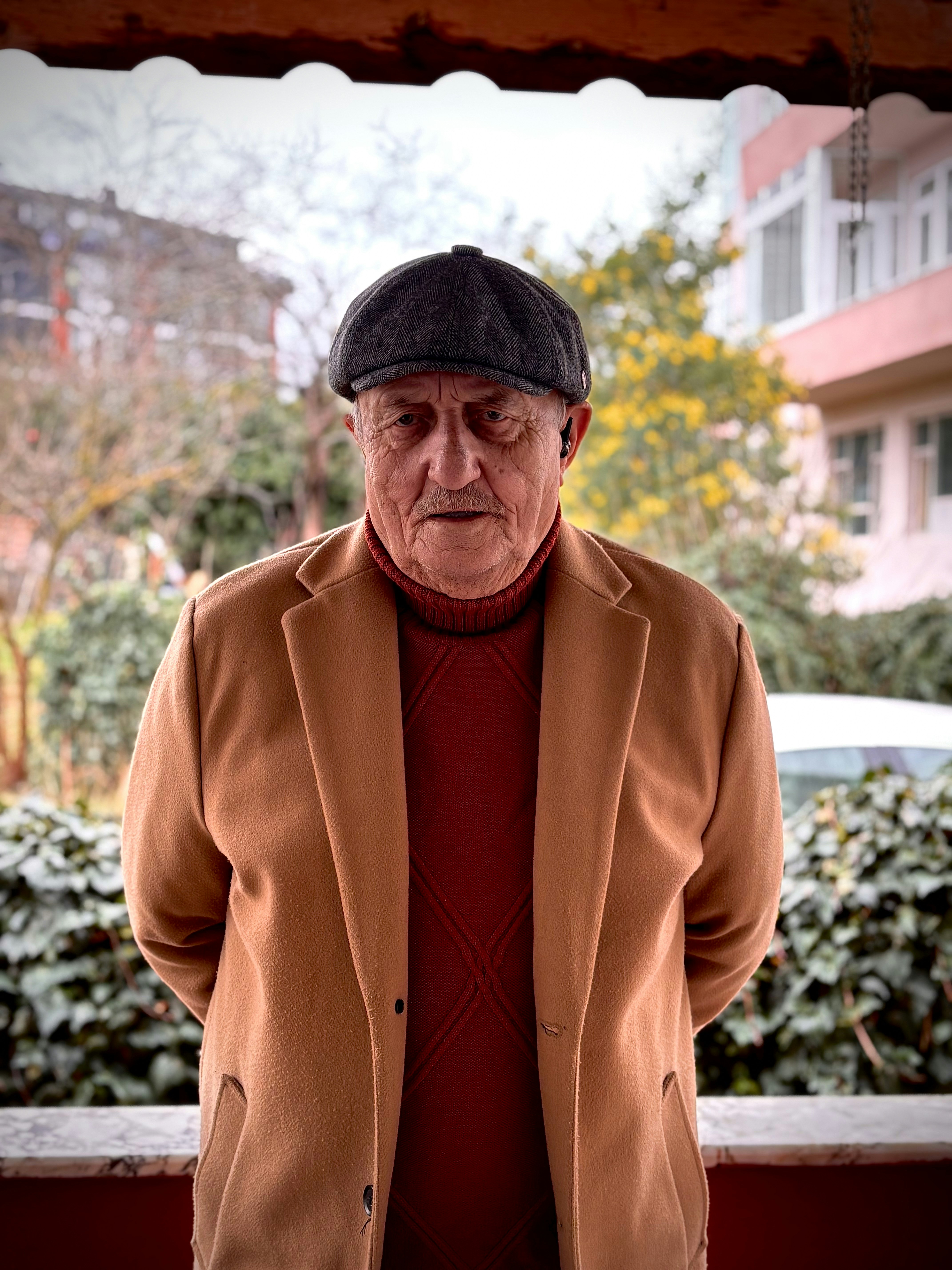 An elderly man wearing a cap and coat