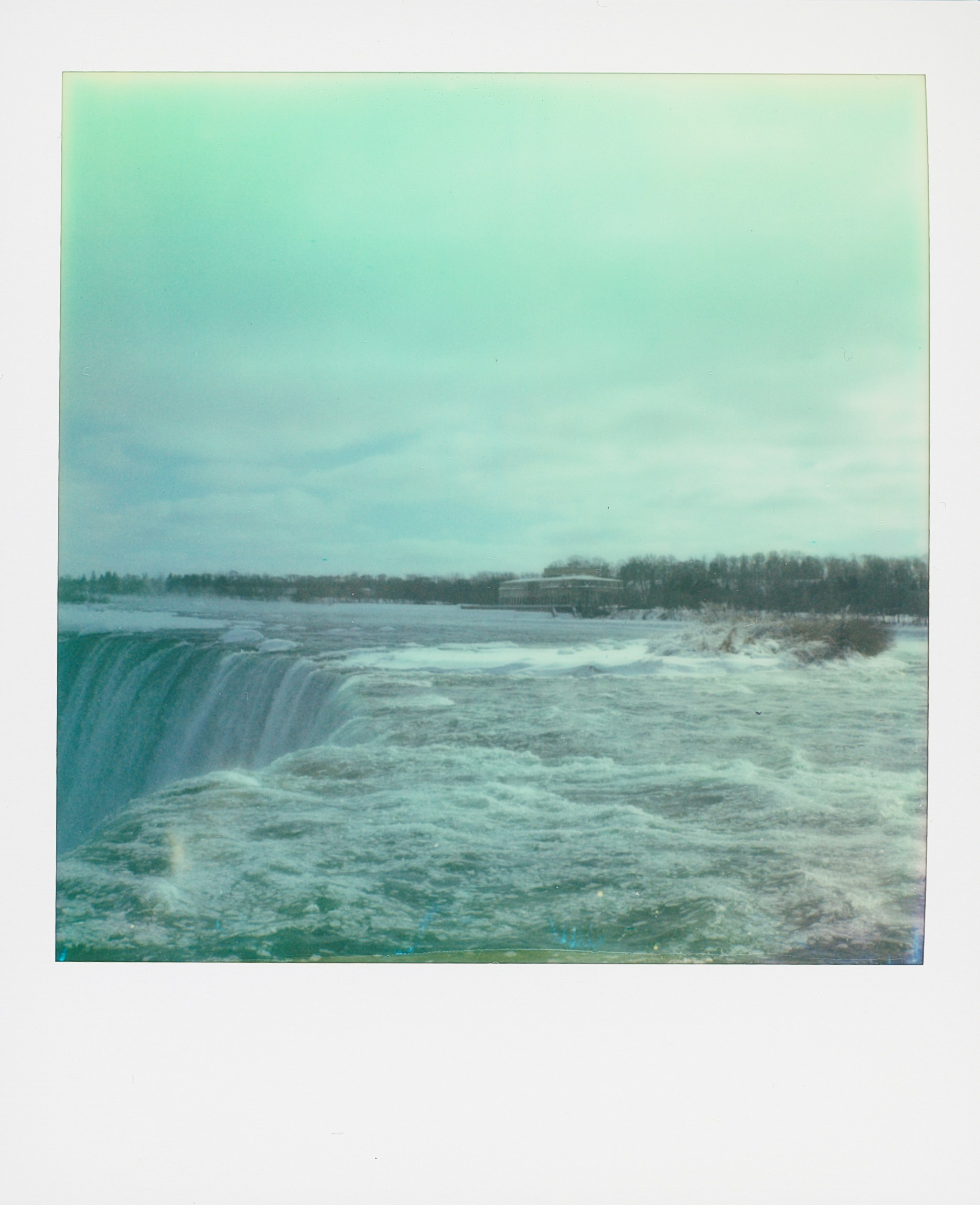 A wide waterfall with turbulent water and a cloudy sky