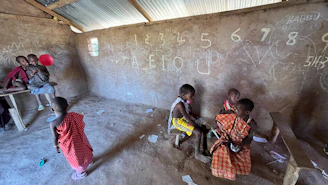 Children in a classroom with numbers on the wall
