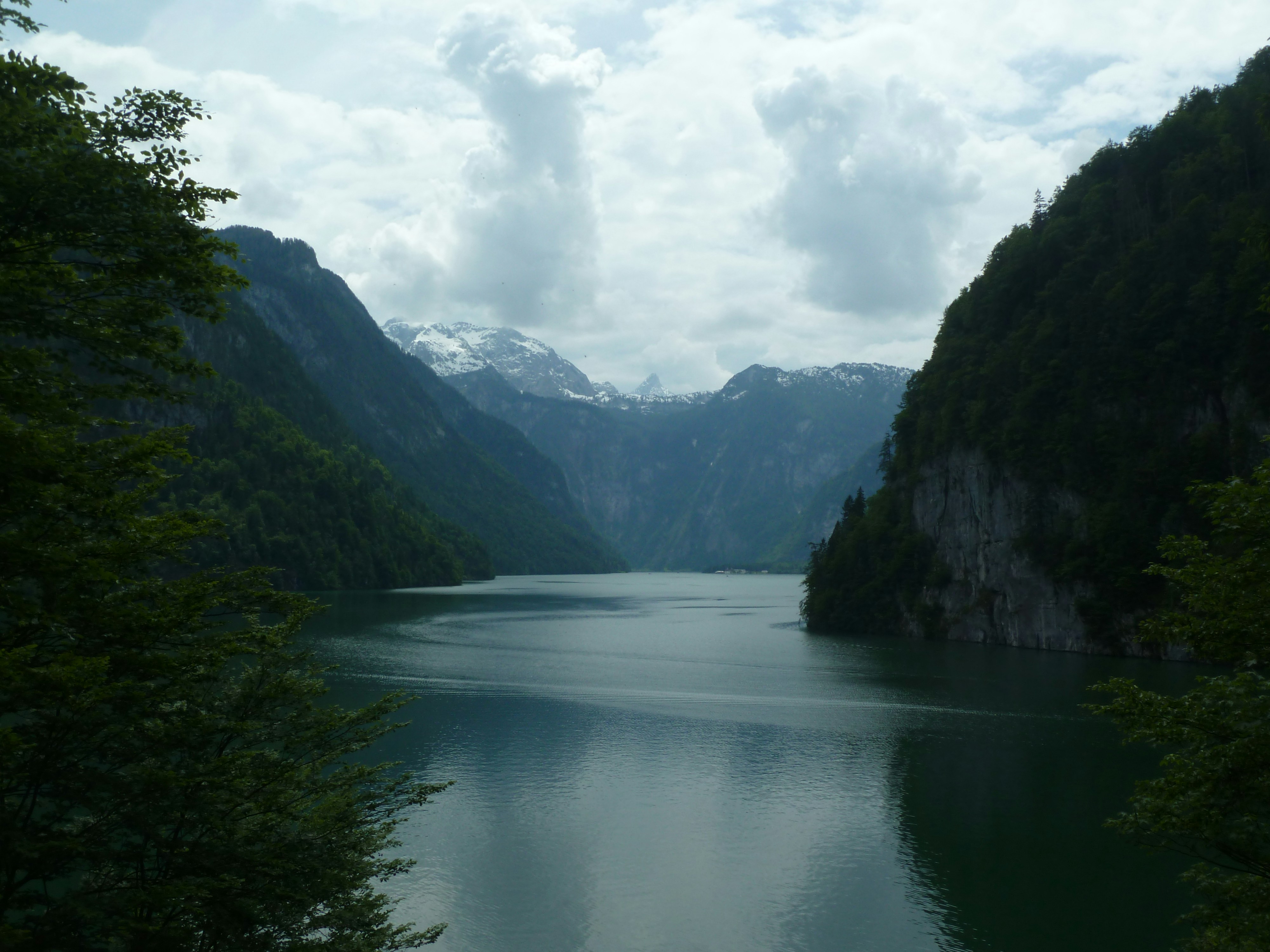 Serene lake surrounded by steep, tree-covered mountains.