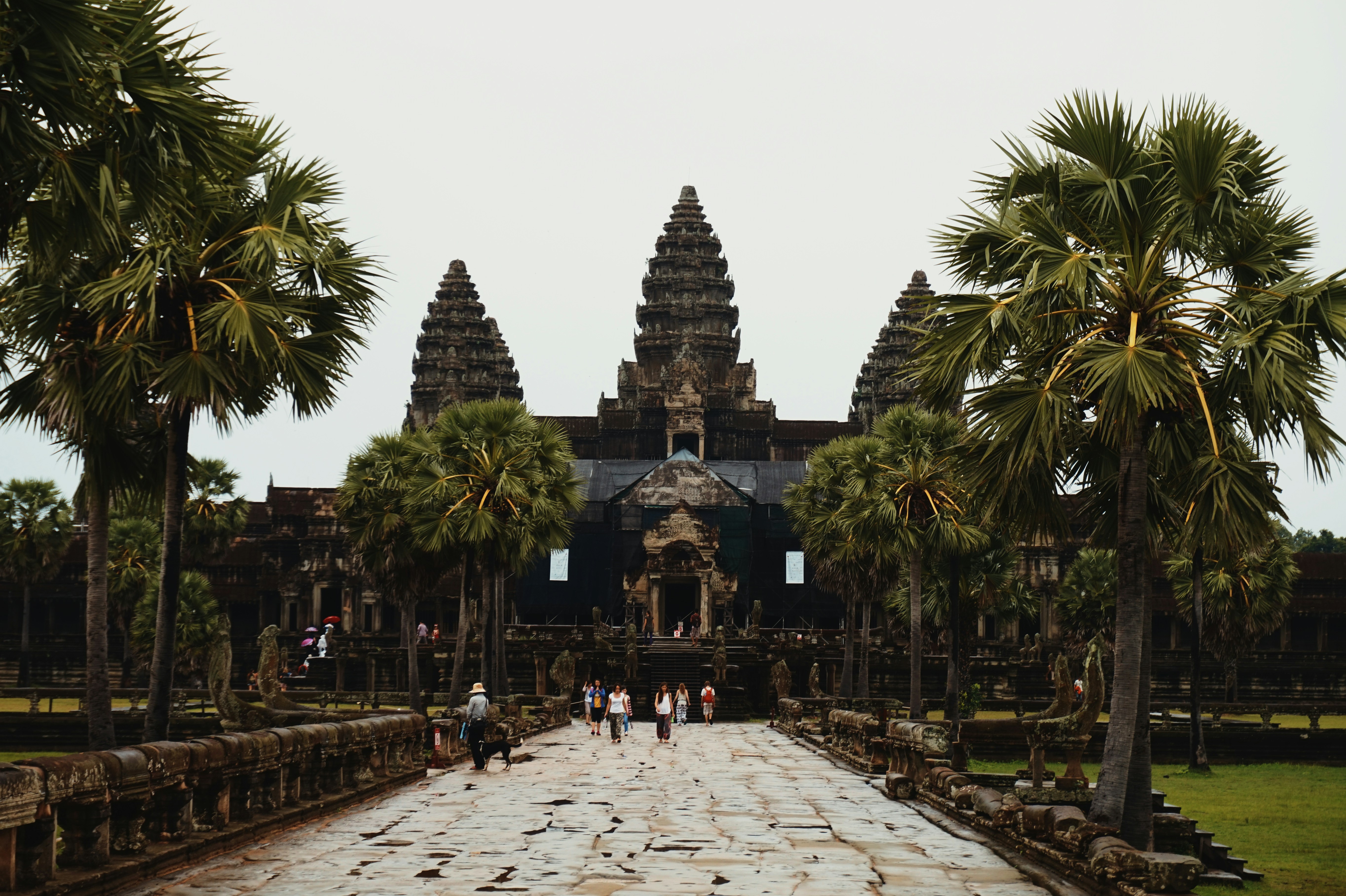 Ancient temple complex with palm trees and people