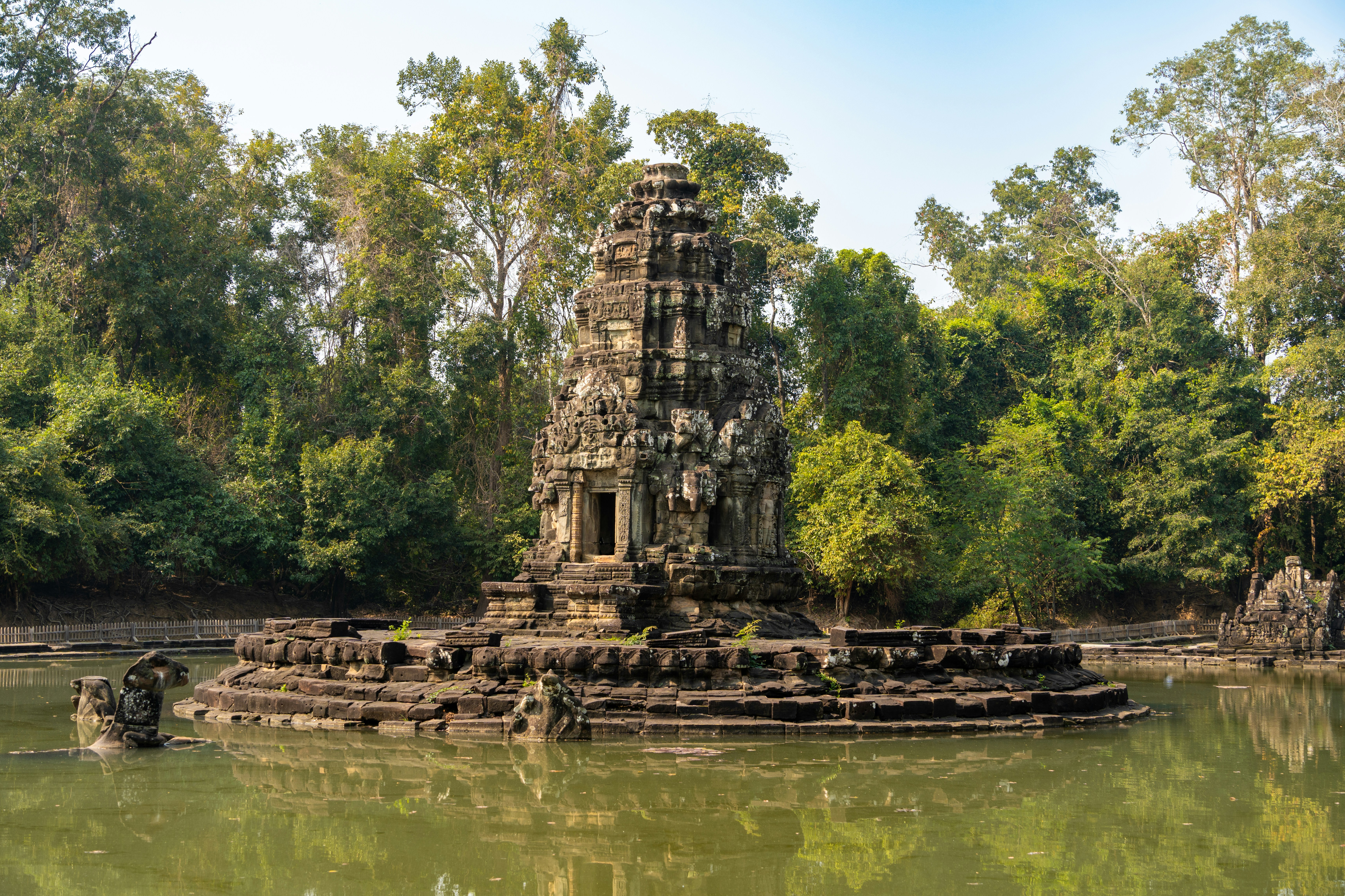 Antiguas ruinas de templos de piedra en un tranquilo estanque de la selva.