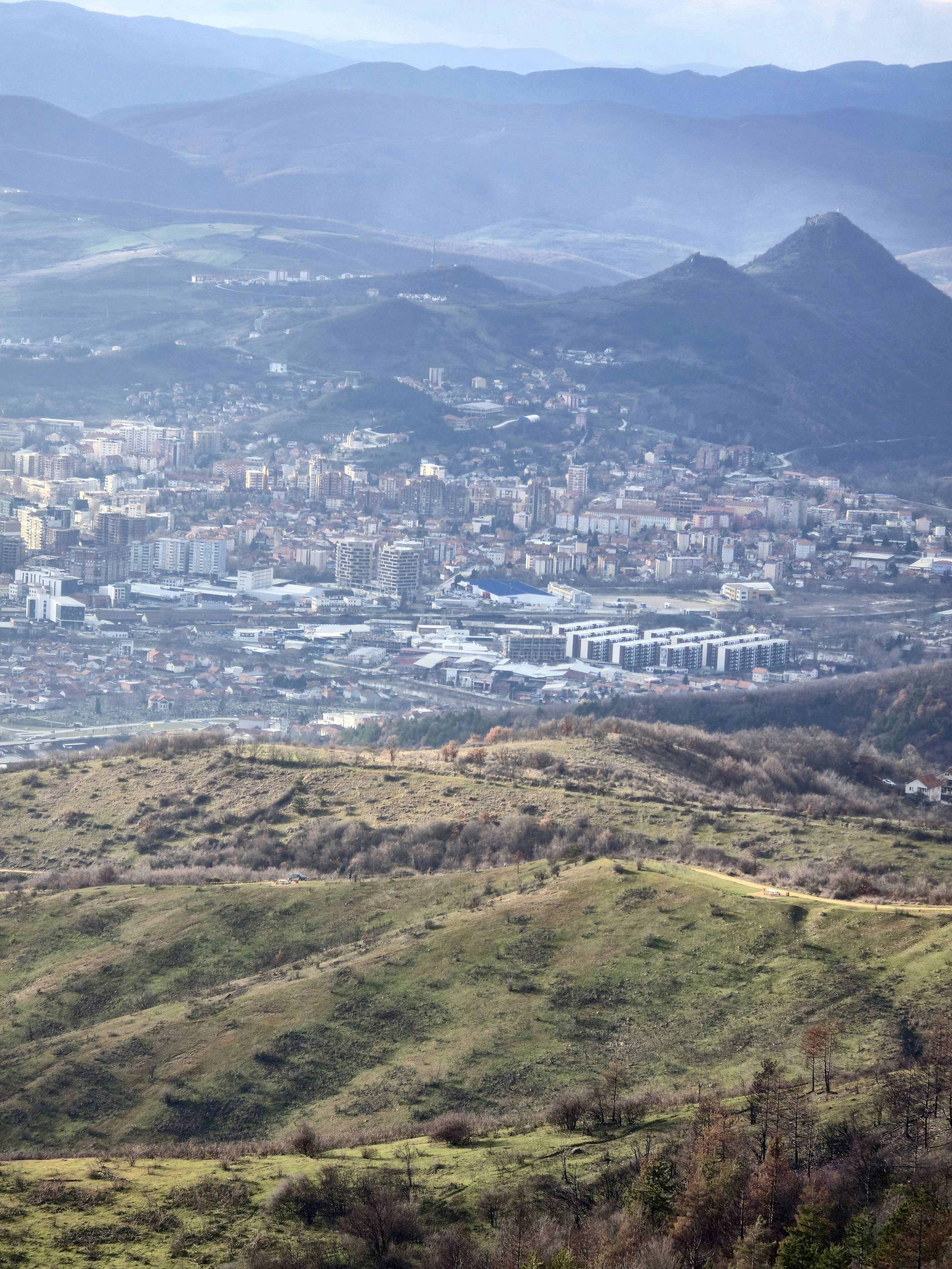 City nestled in rolling hills under hazy sky