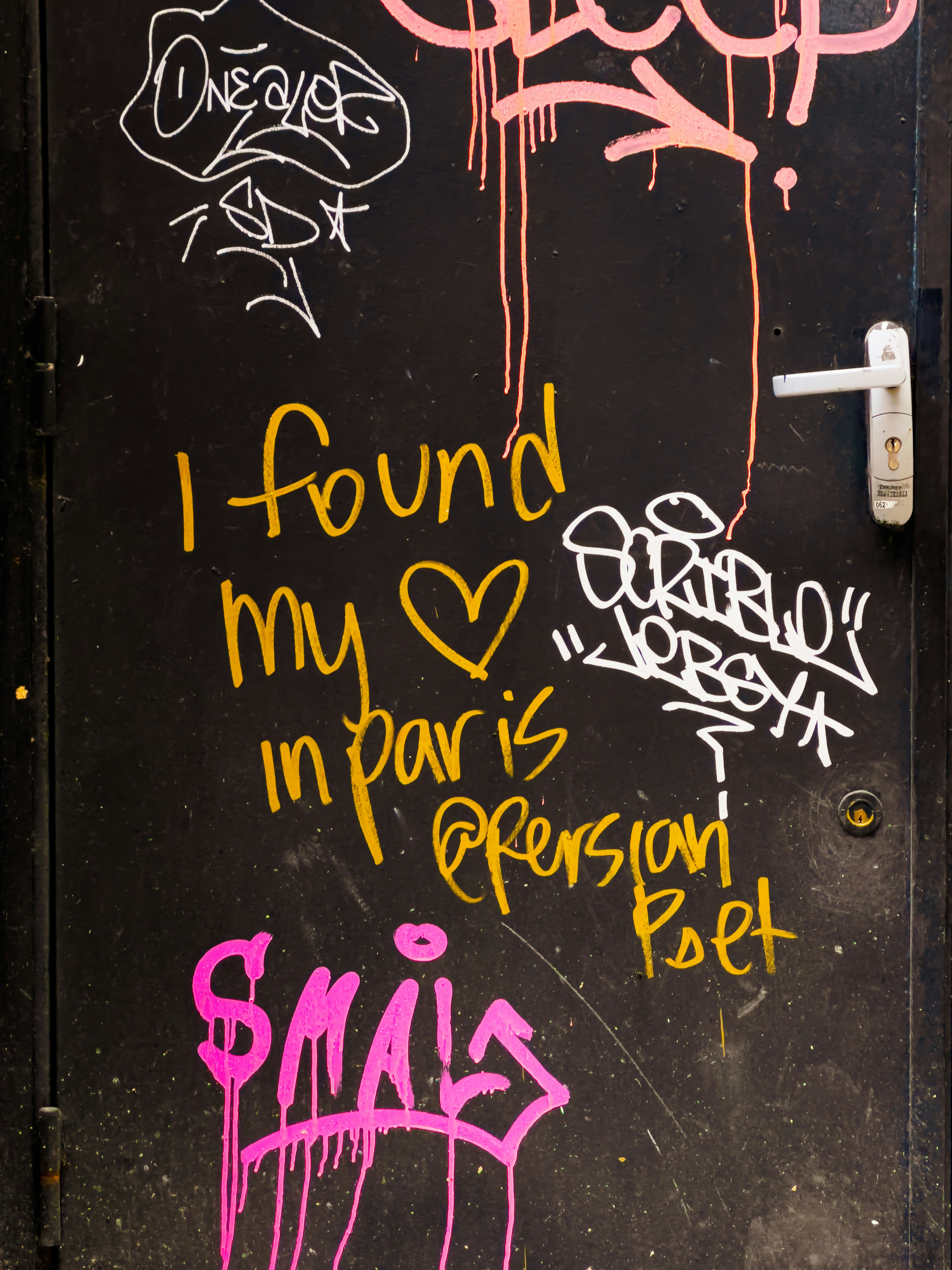 Graffiti on a black door with a white handle.