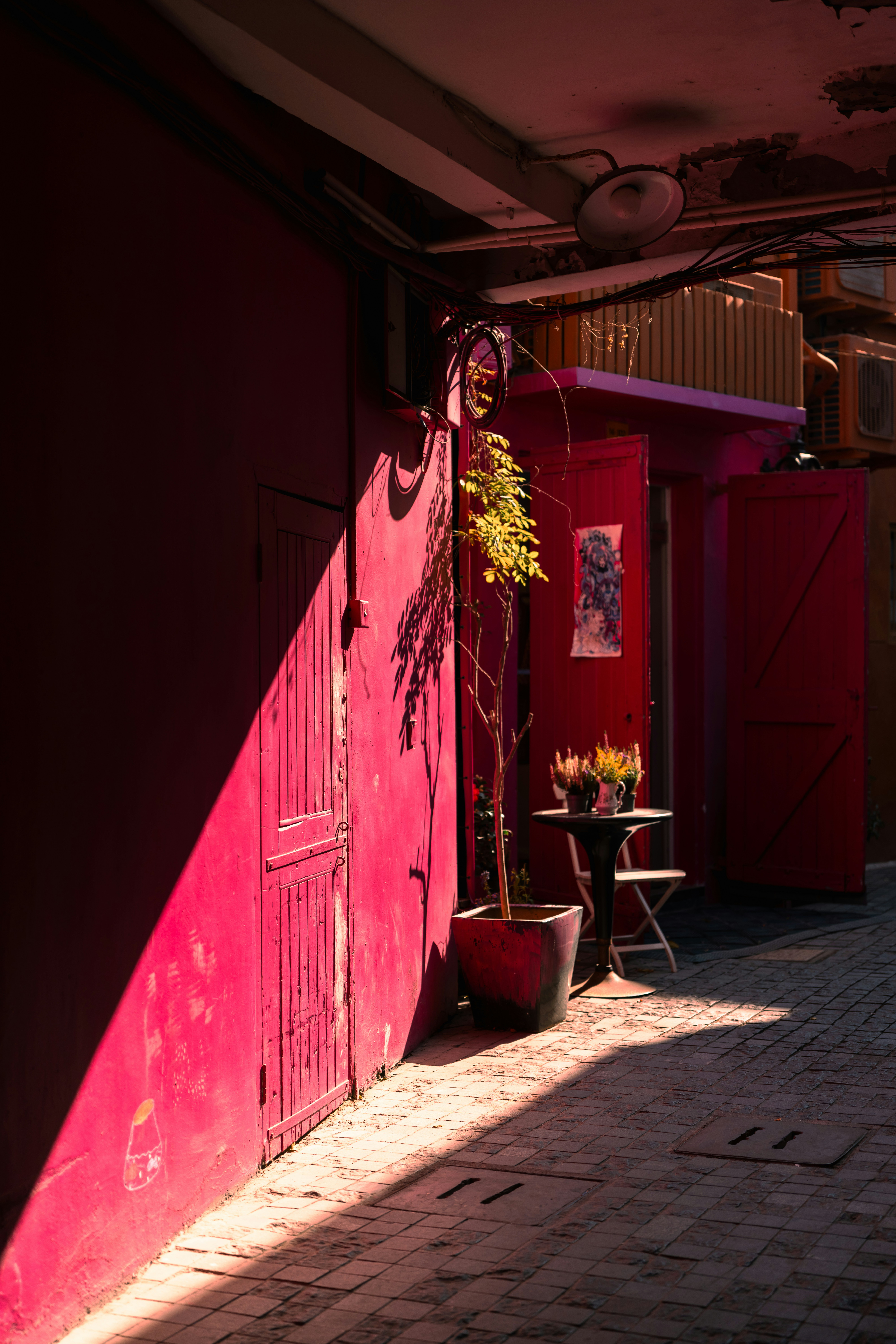 A narrow alleyway with bright pink walls and sunlight.