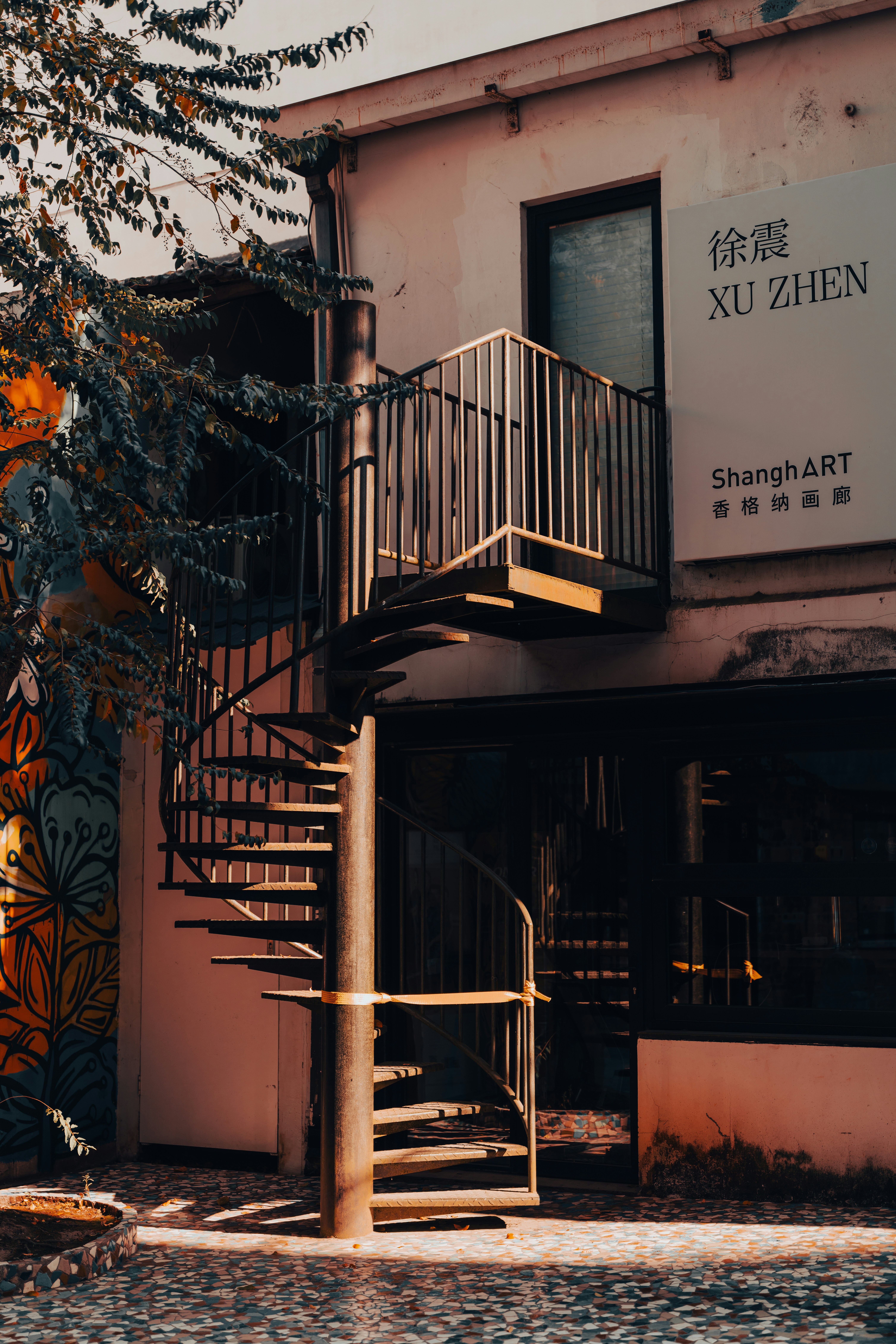 Outdoor spiral staircase leads to a building entrance.