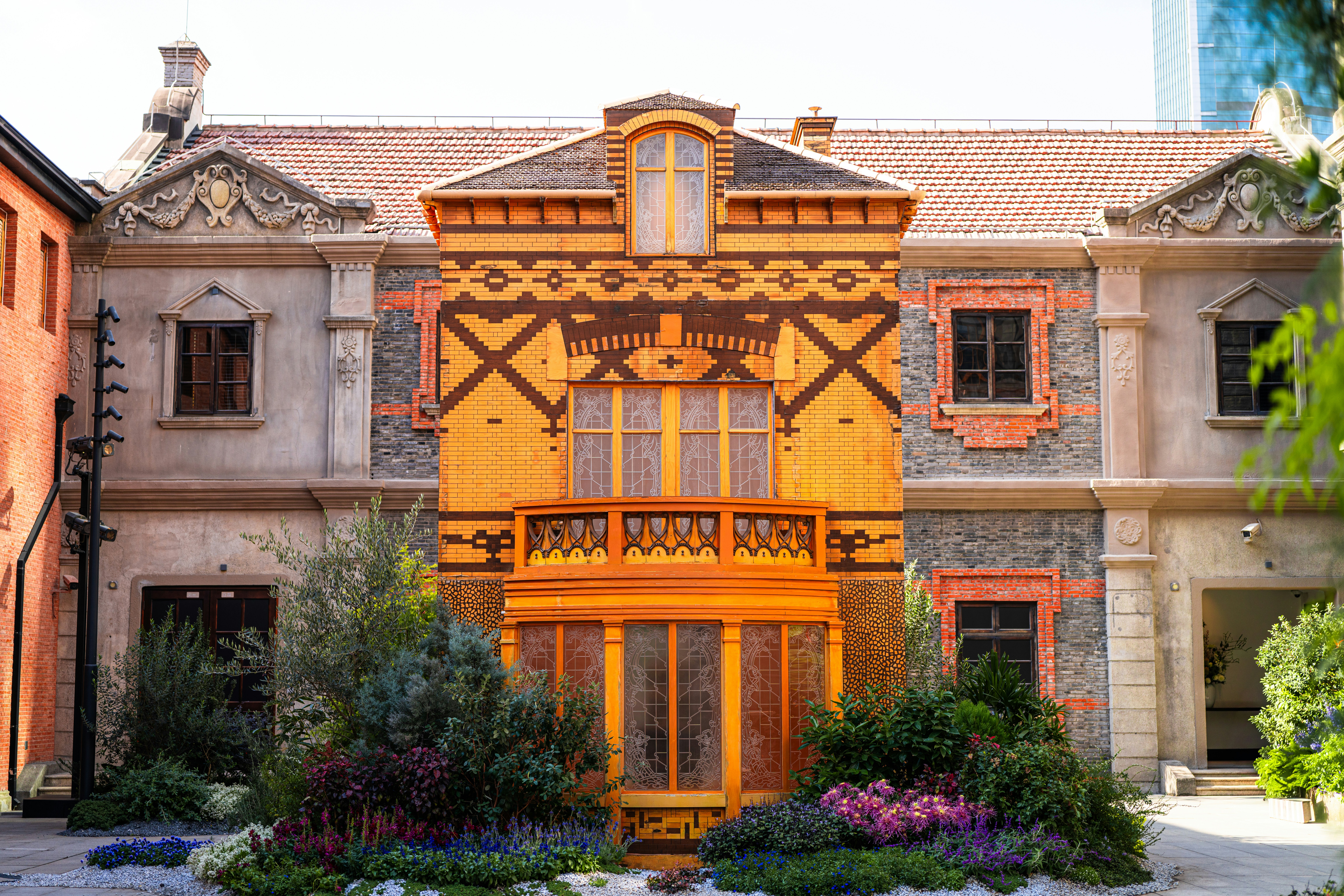 Ornate orange building facade with decorative windows and plants