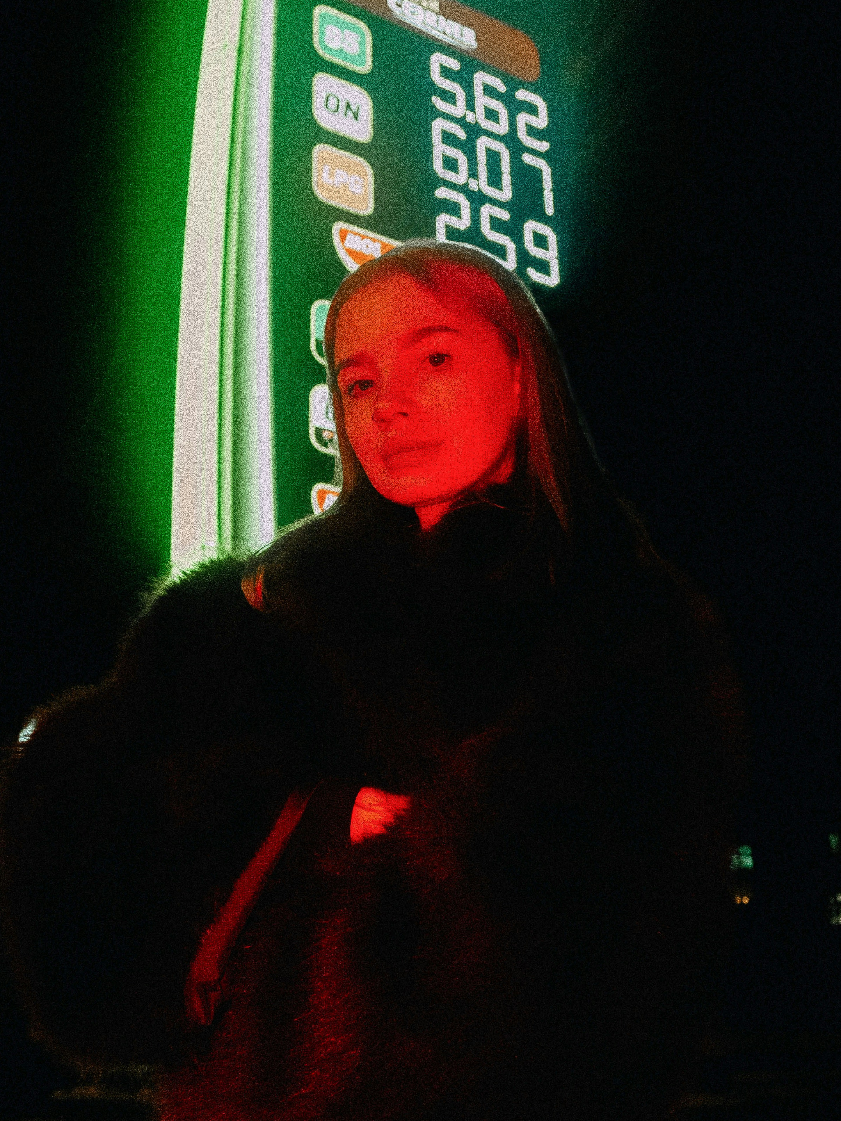 Young woman illuminated by red light at gas station
