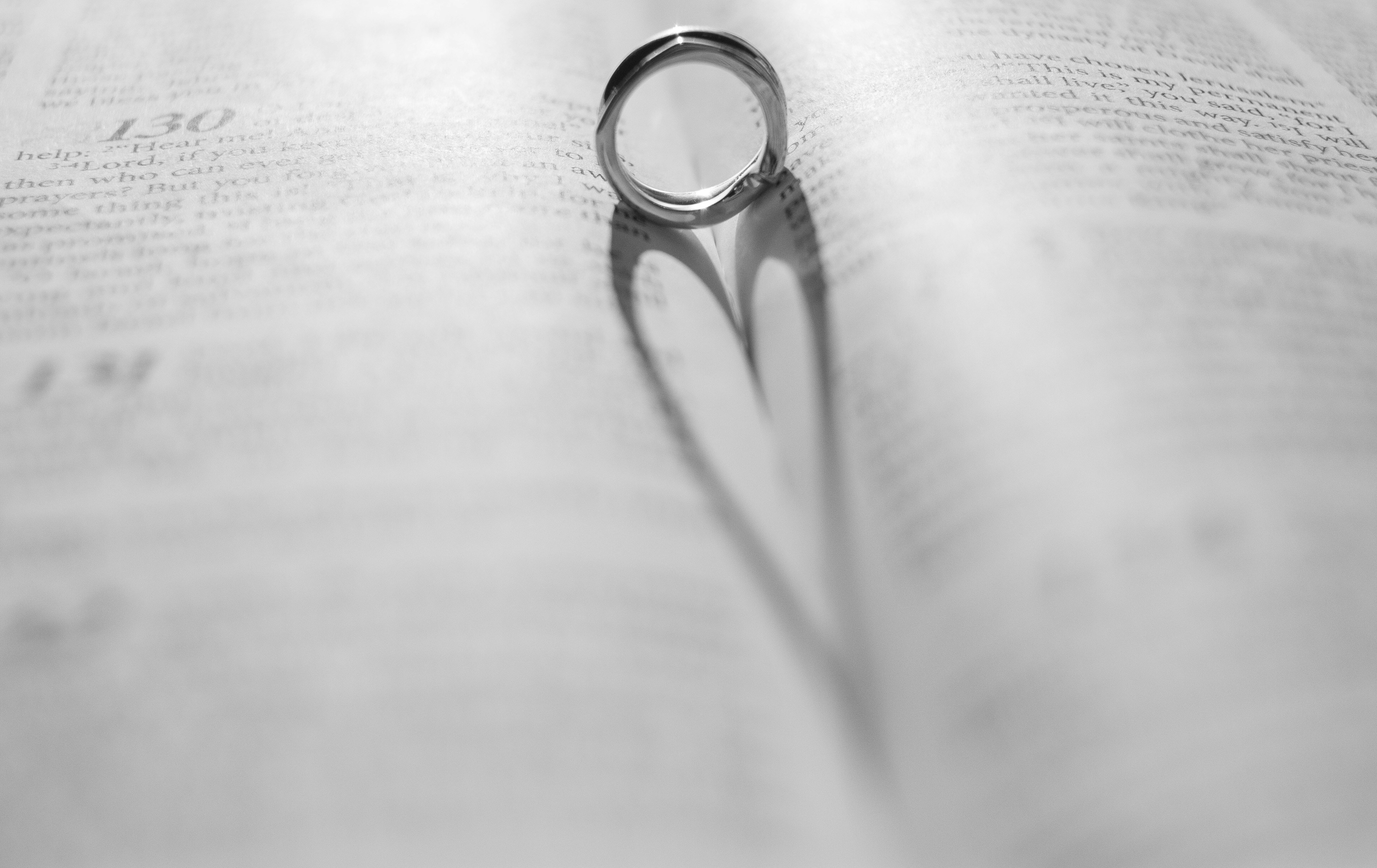 Ein Ring wirft einen herzförmigen Schatten auf ein Buch.