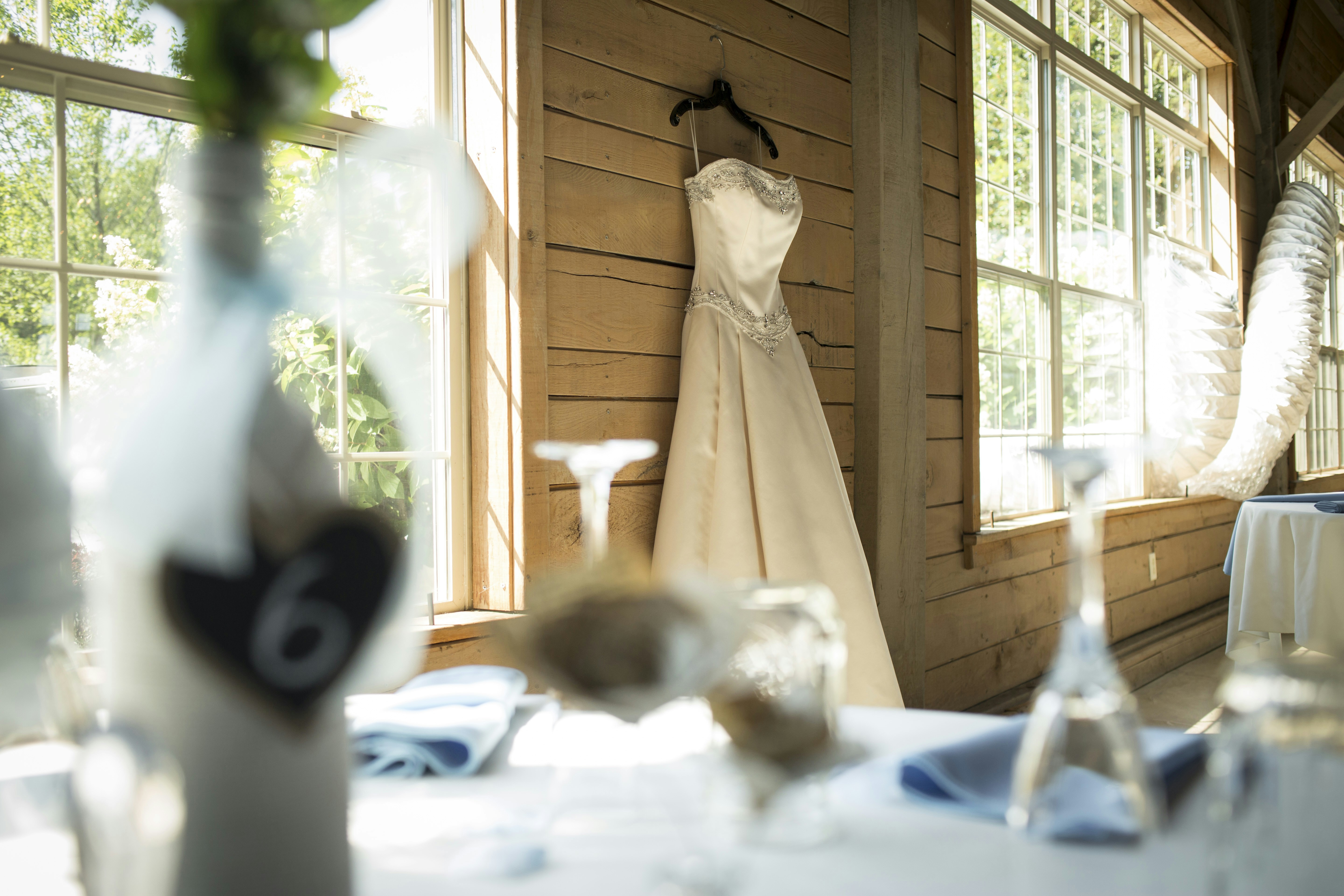 Ein weißes Hochzeitskleid hängt neben einem Fenster.