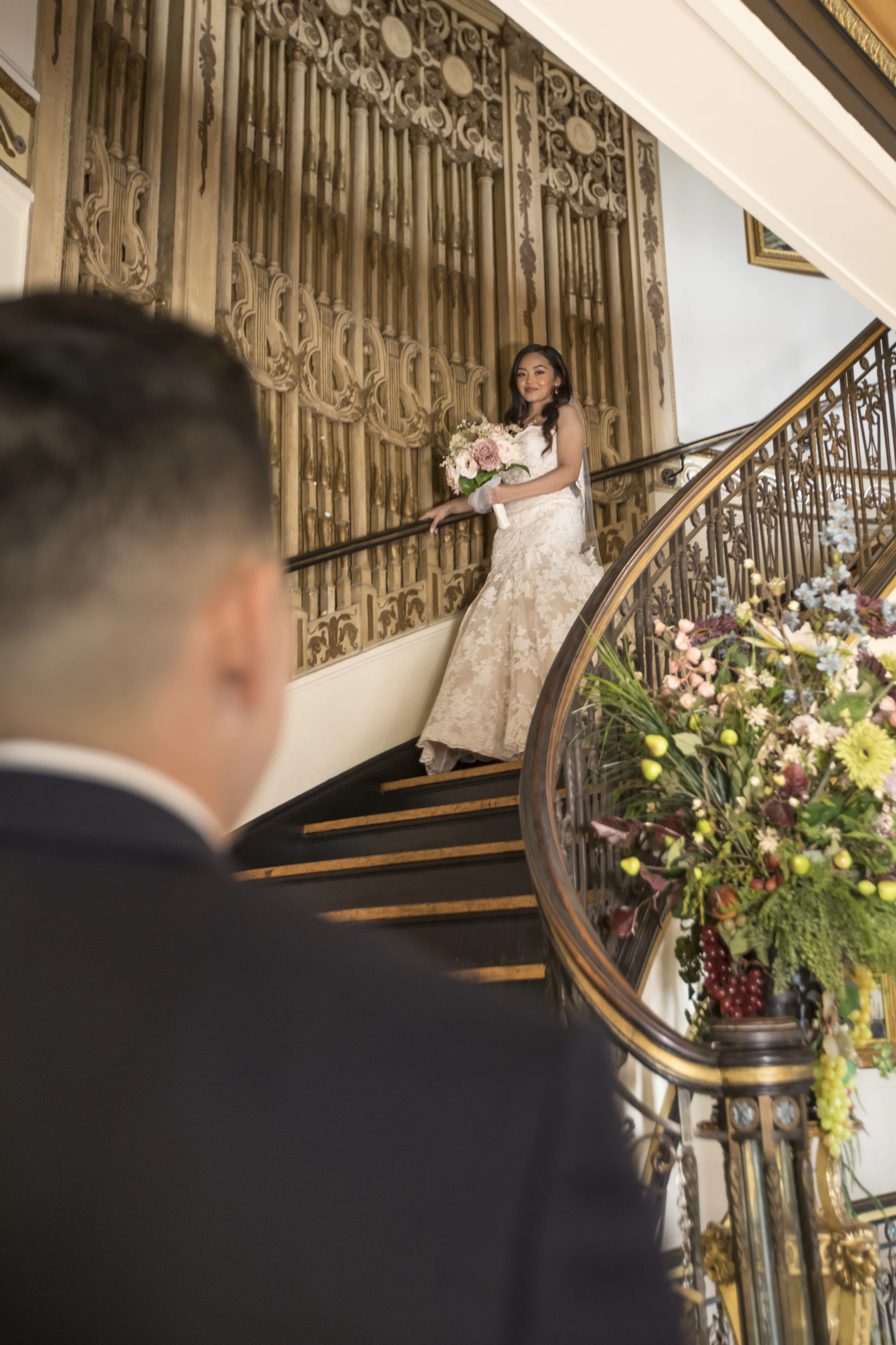 Bride in a wedding dress holding flowers on an ornate staircase