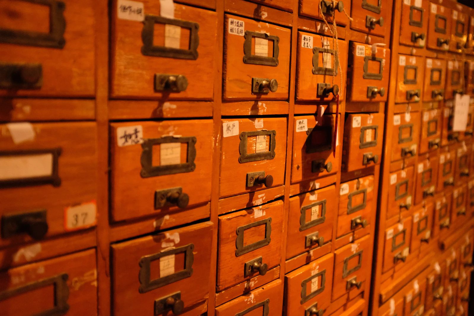 A wall of vintage wooden filing cabinet drawers with small labeled fronts, standing for organized record keeping
