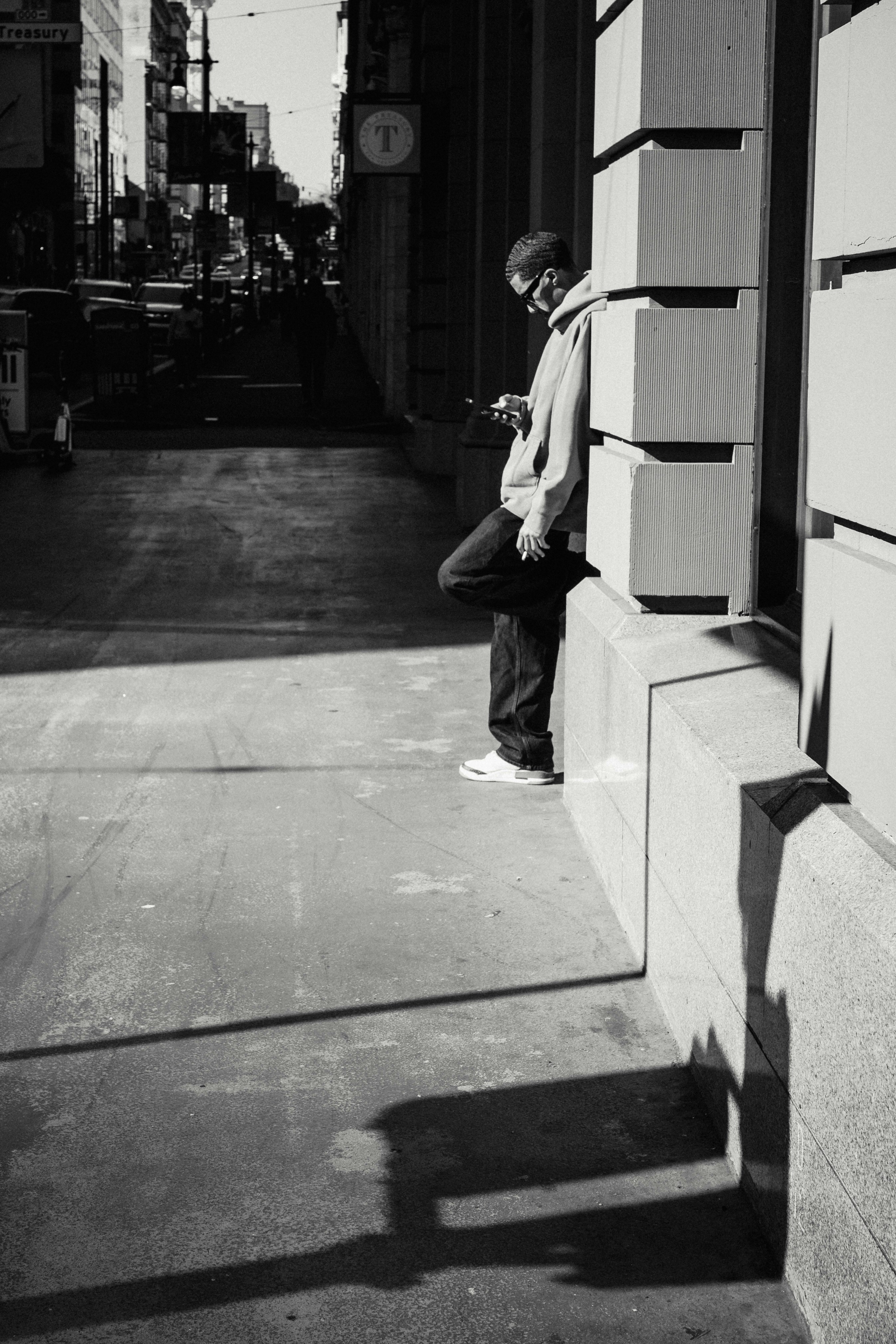 Man looking at phone on a sunny city street