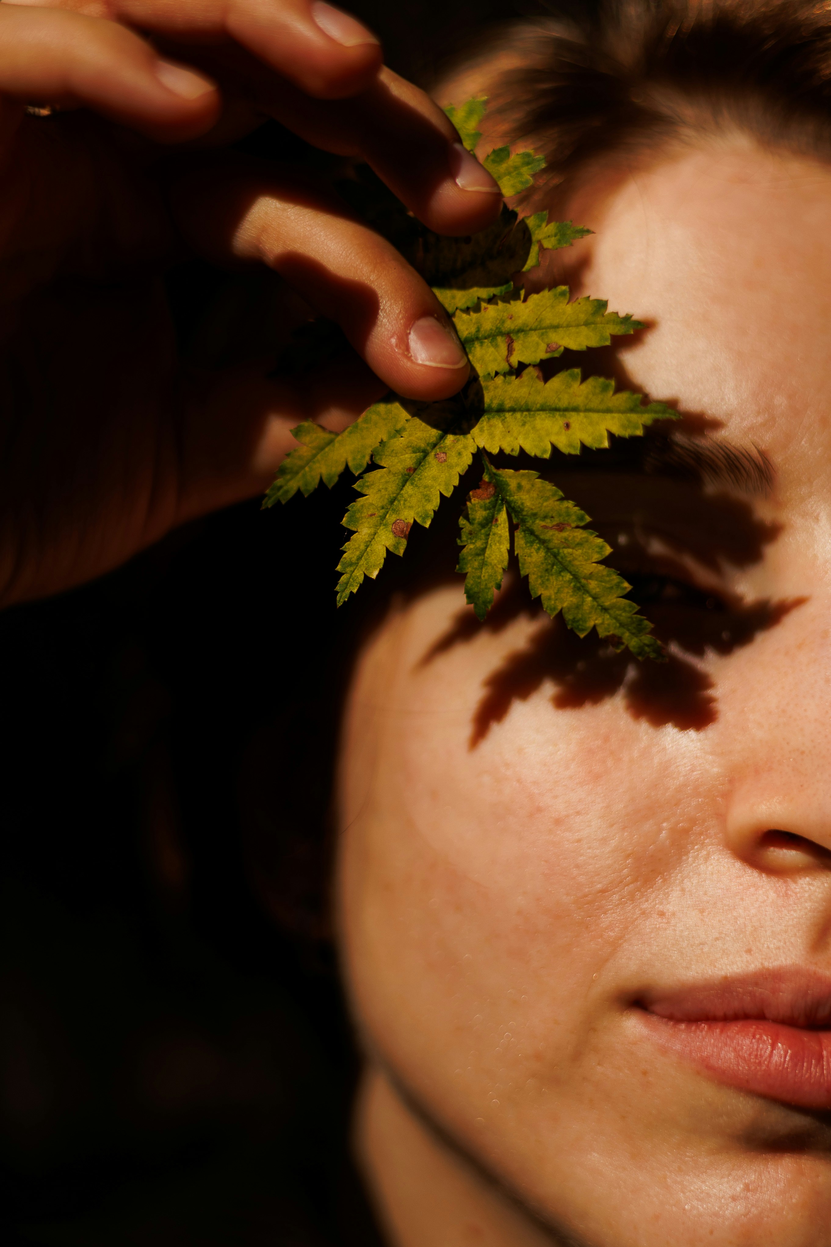 Woman holding a fern leaf over her eye