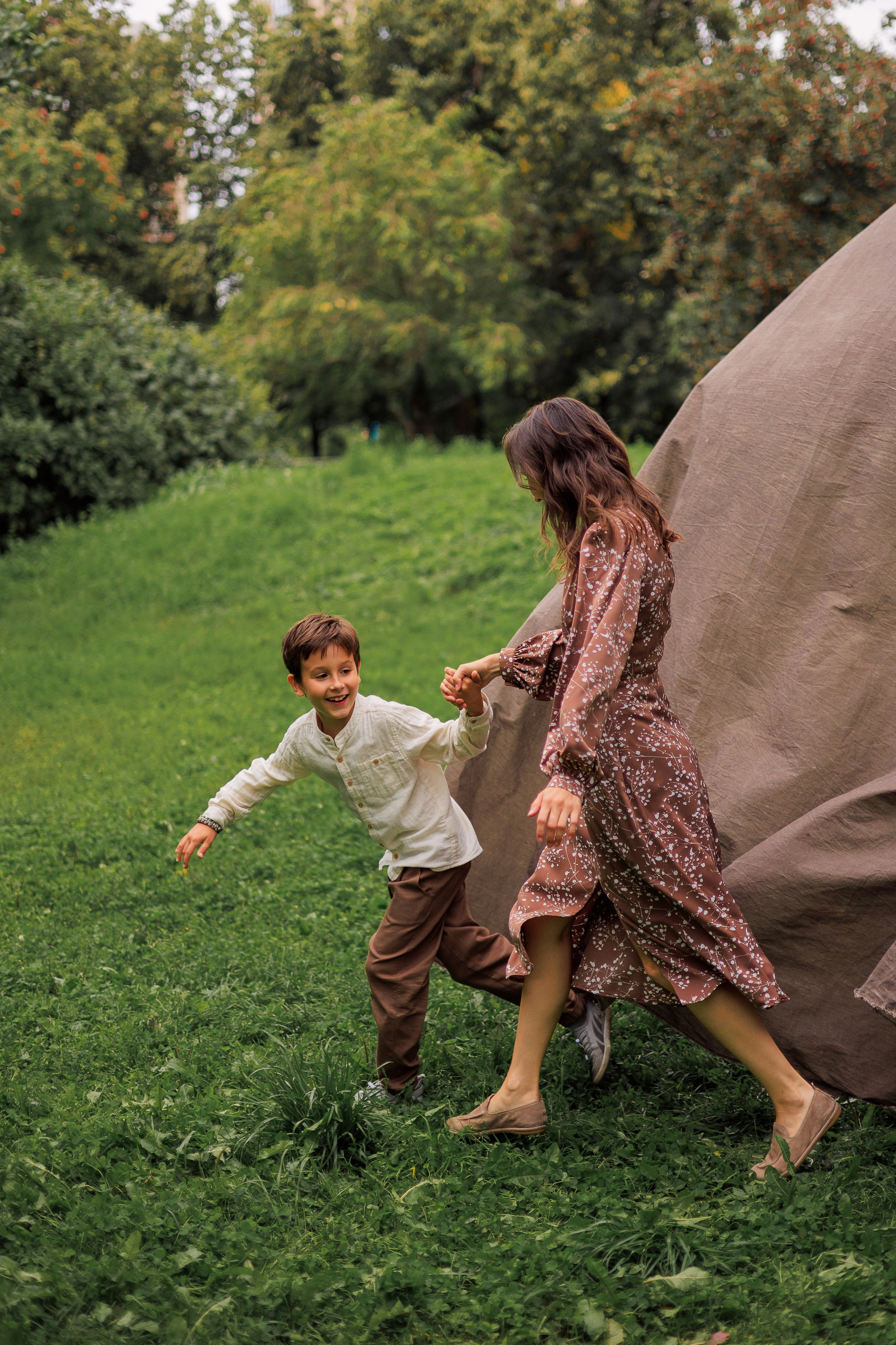 Eine Frau und ein Kind, die in einem grasbewachsenen Park spazieren gehen.