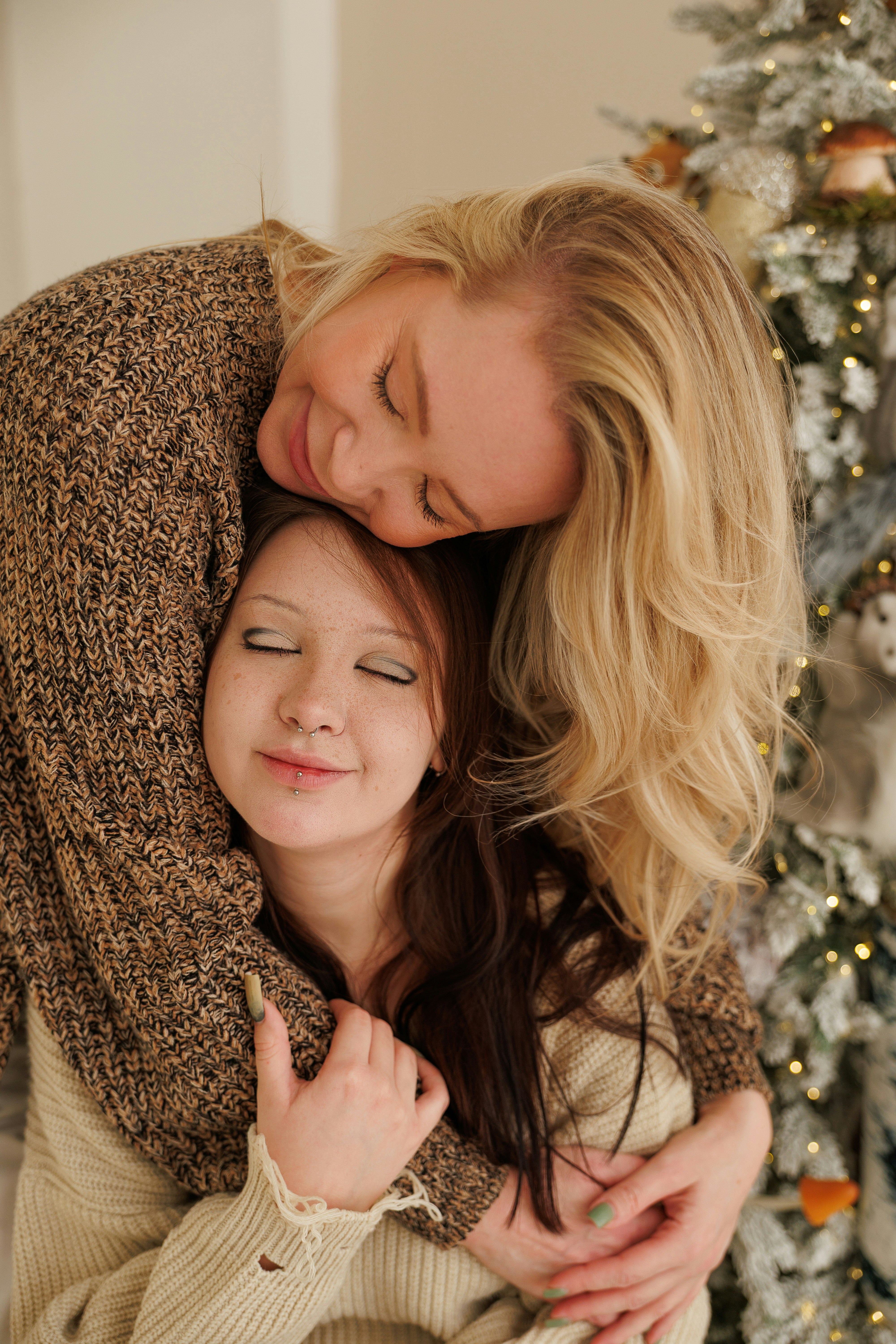 Mutter und Tochter umarmen sich in der Nähe des Weihnachtsbaums