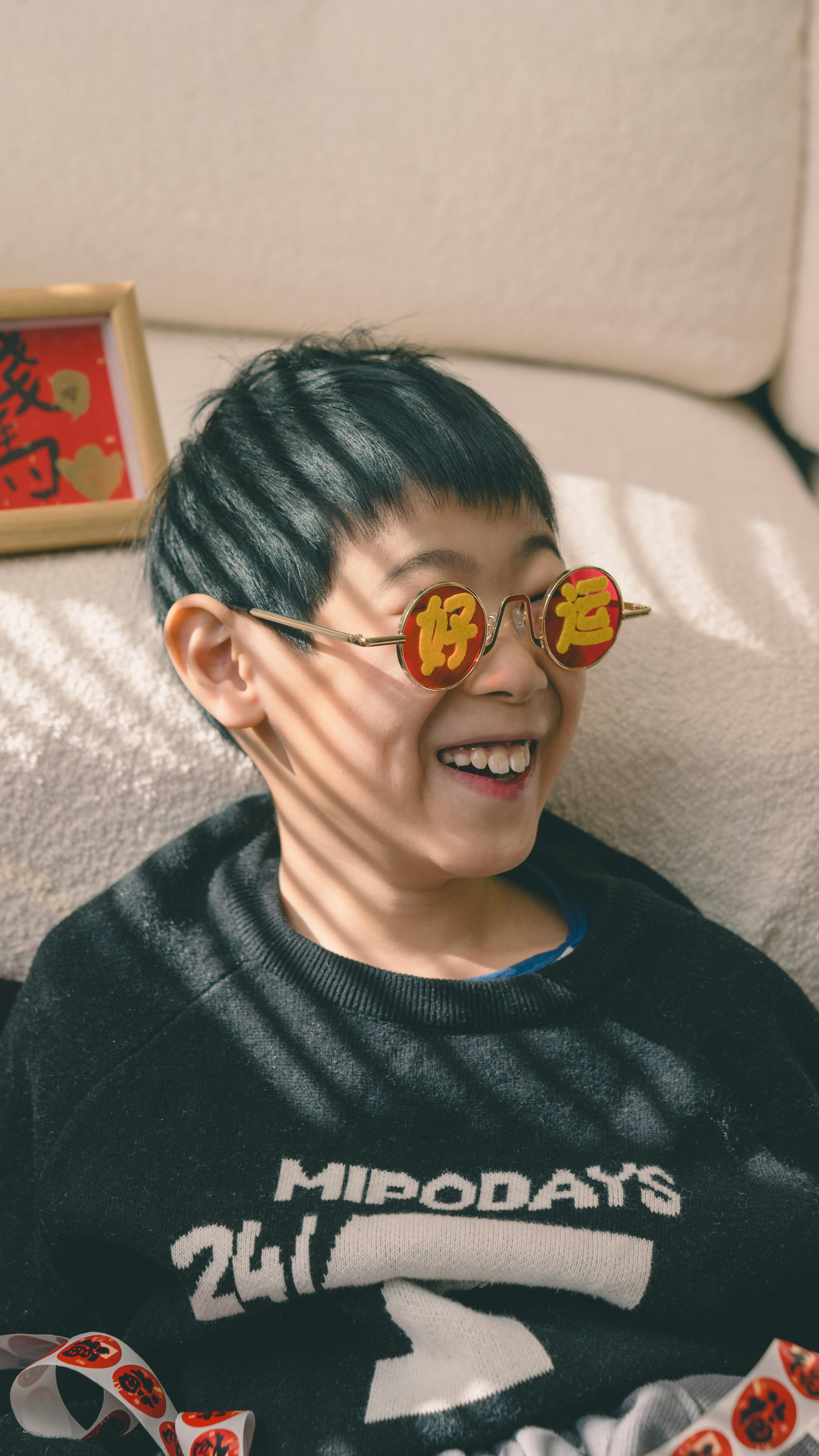 Ein lächelnder Junge trägt runde Sonnenbrillen mit chinesischen Schriftzeichen.