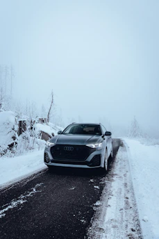 A grey audi drives on a snowy road