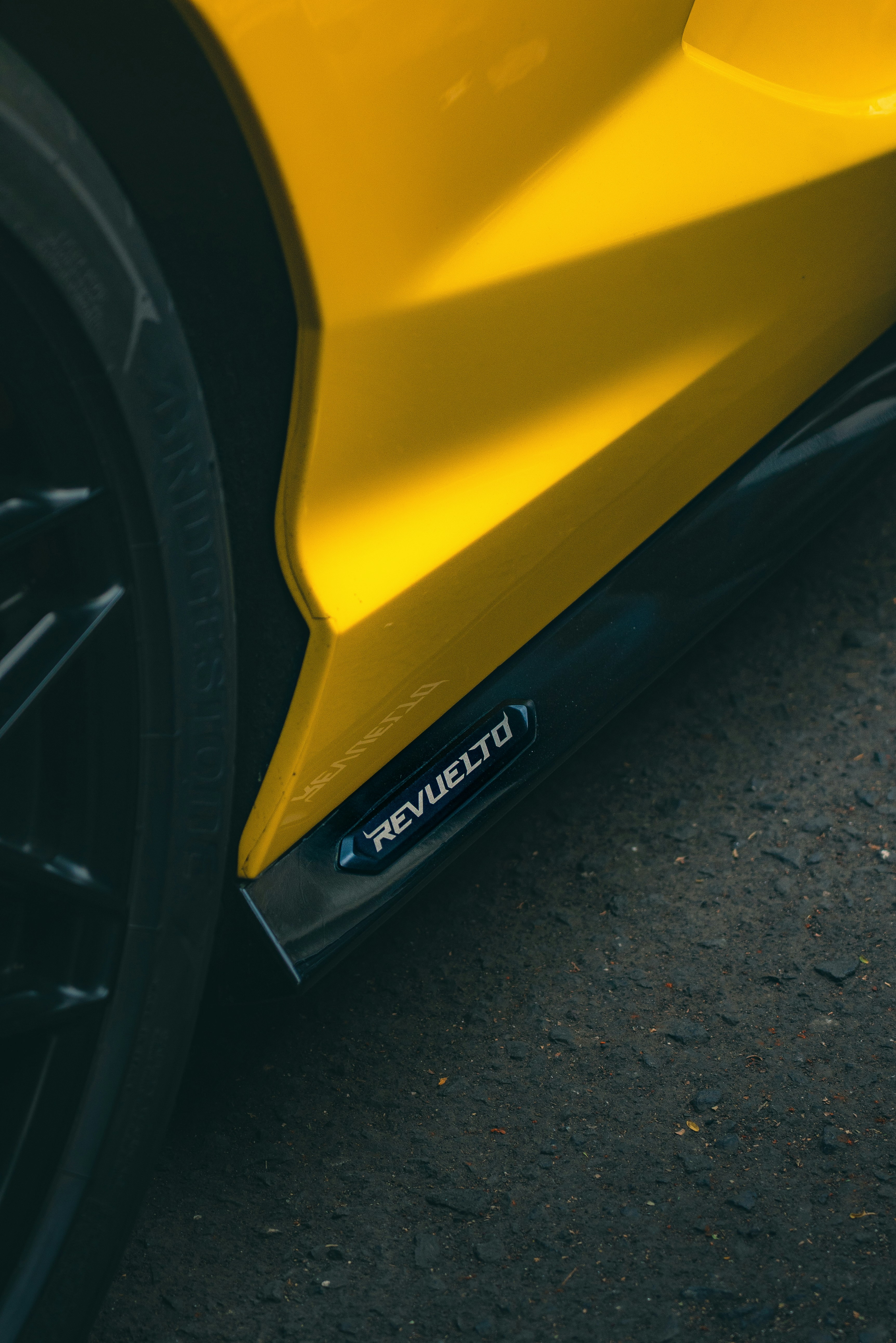 Close-up of a yellow sports car with 'revuelto' emblem.