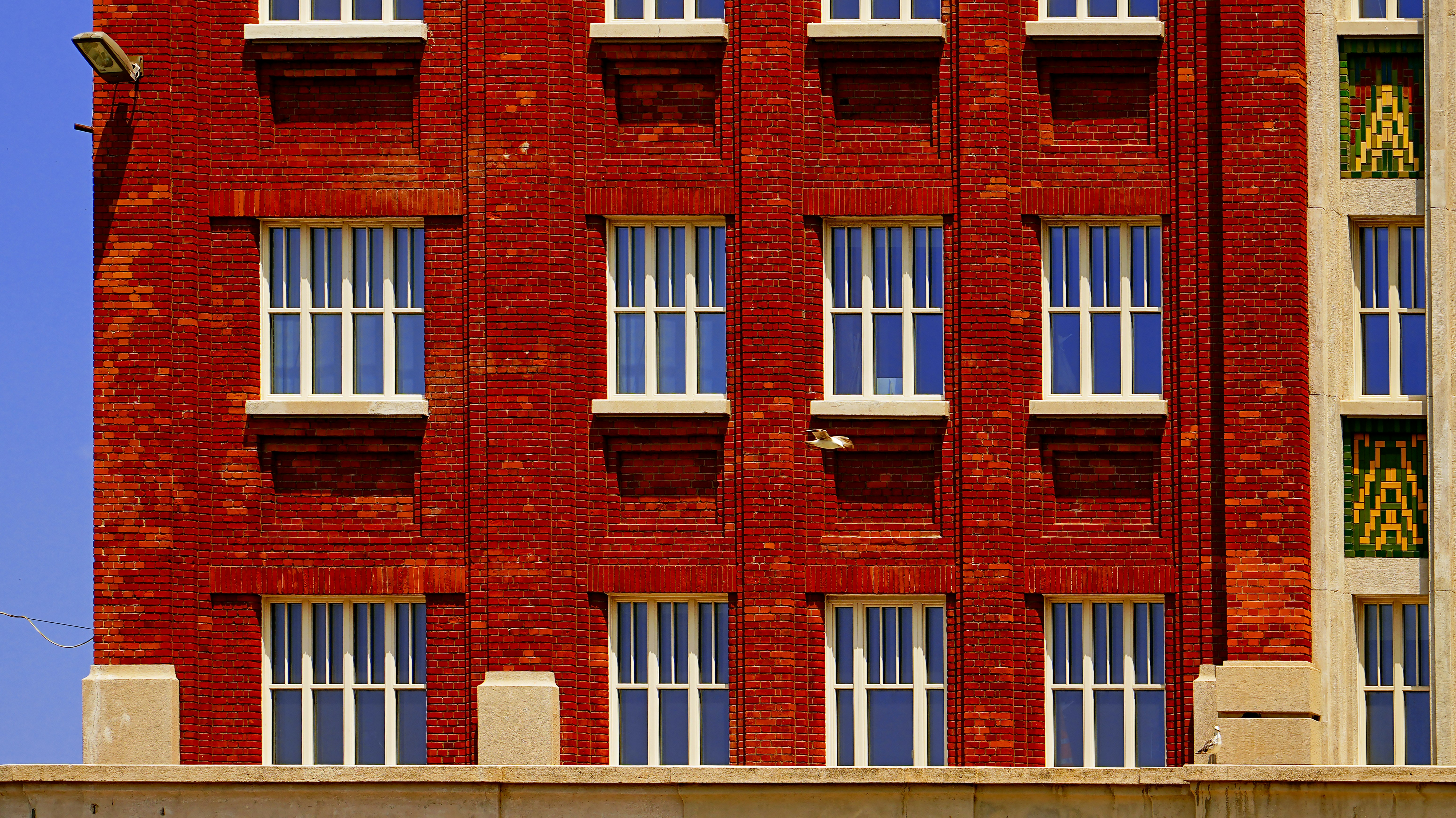 Fassade des roten Backsteingebäudes mit weißen Rahmenfenstern.