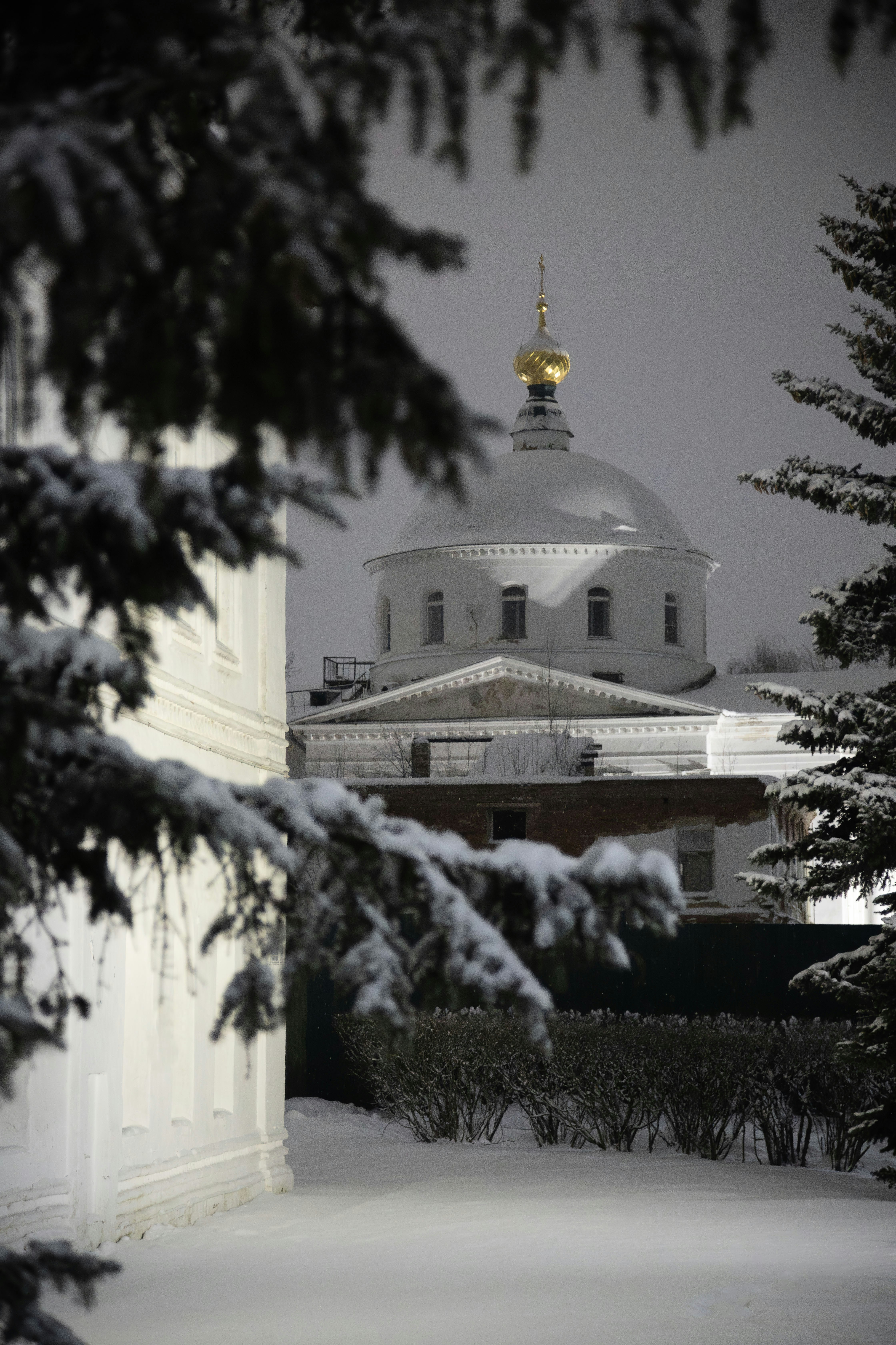 Snow-covered building with a golden dome at night