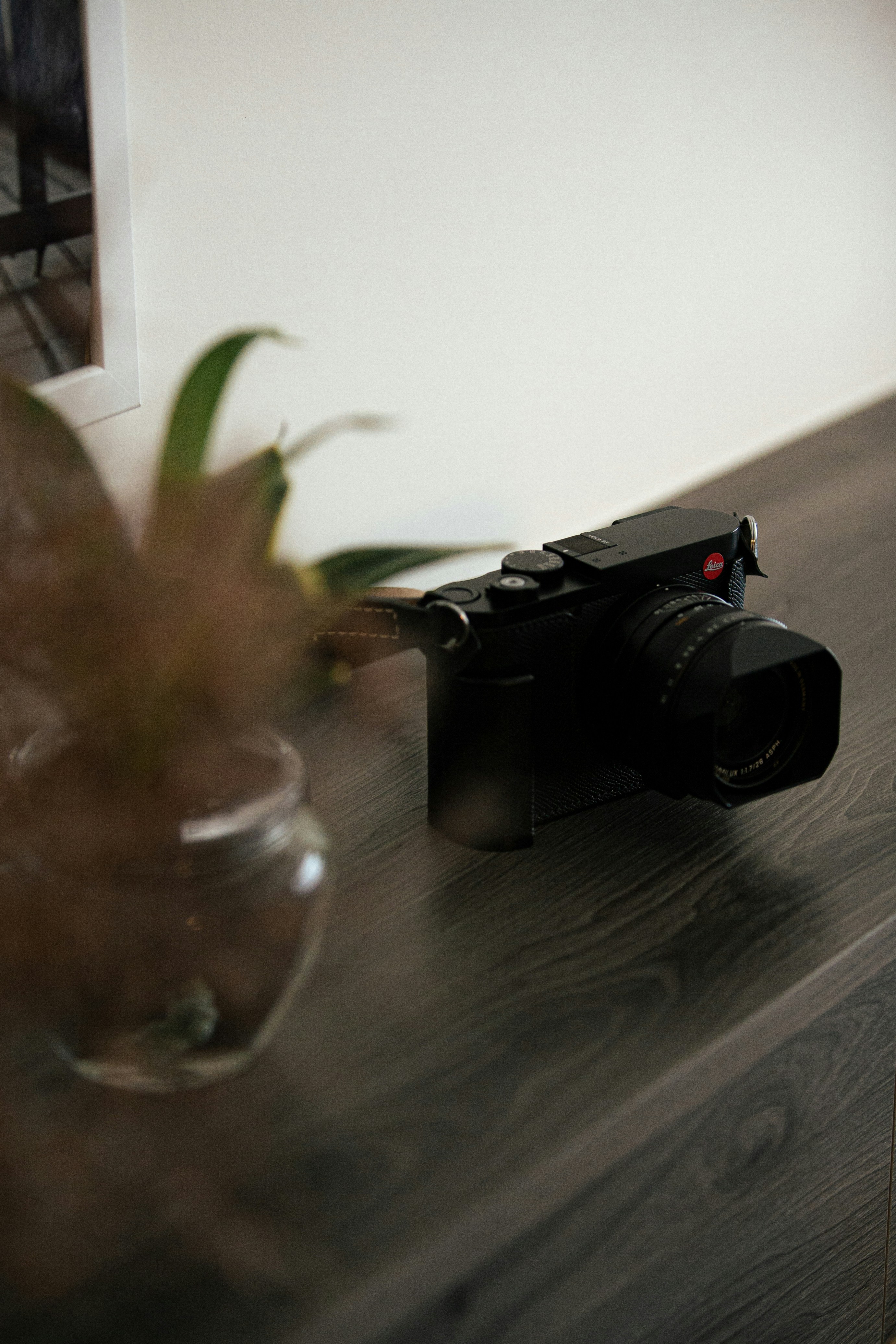 A black camera rests on a wooden surface.