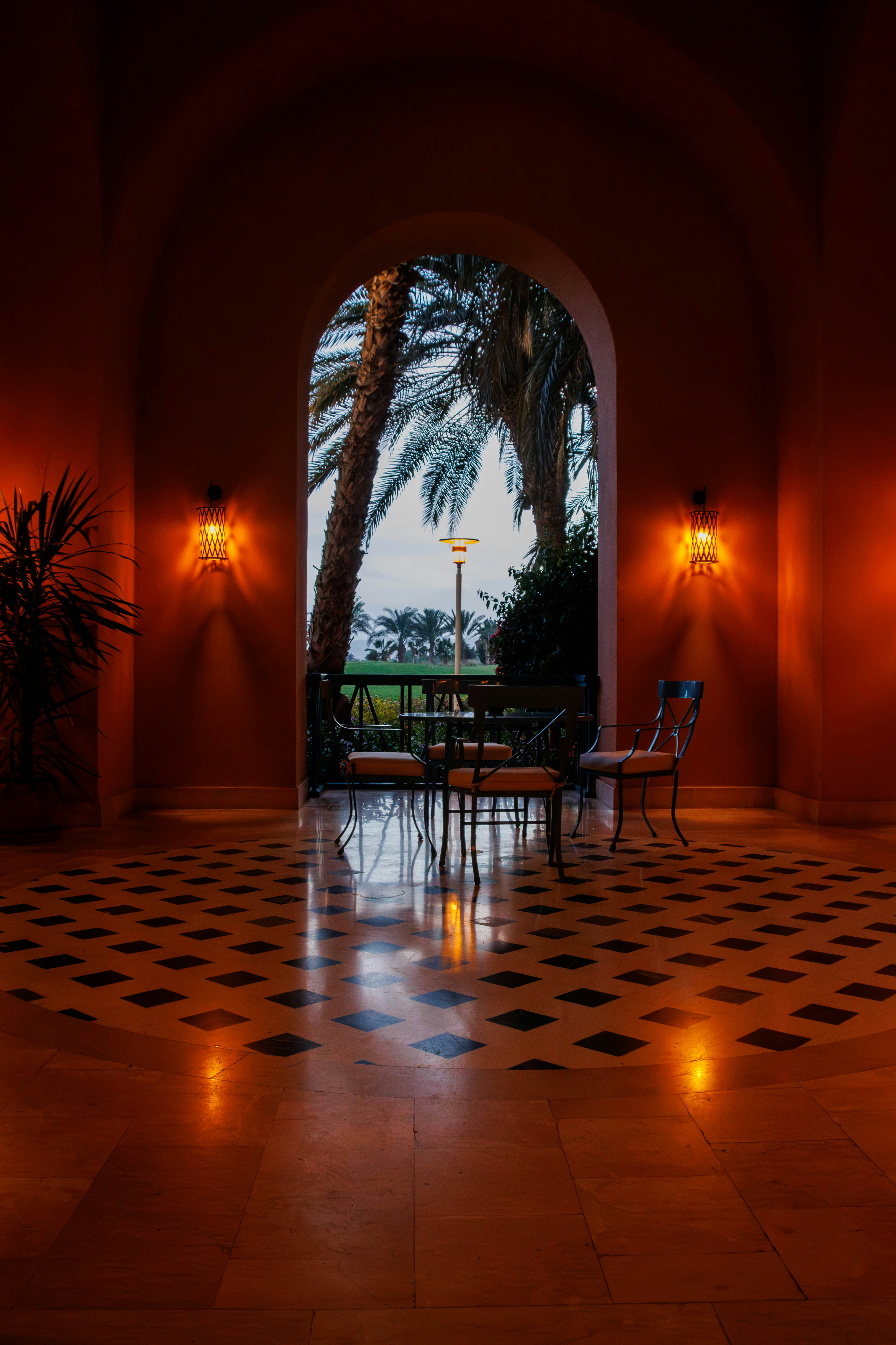 Arched walkway with ornate floor and outdoor seating area beyond