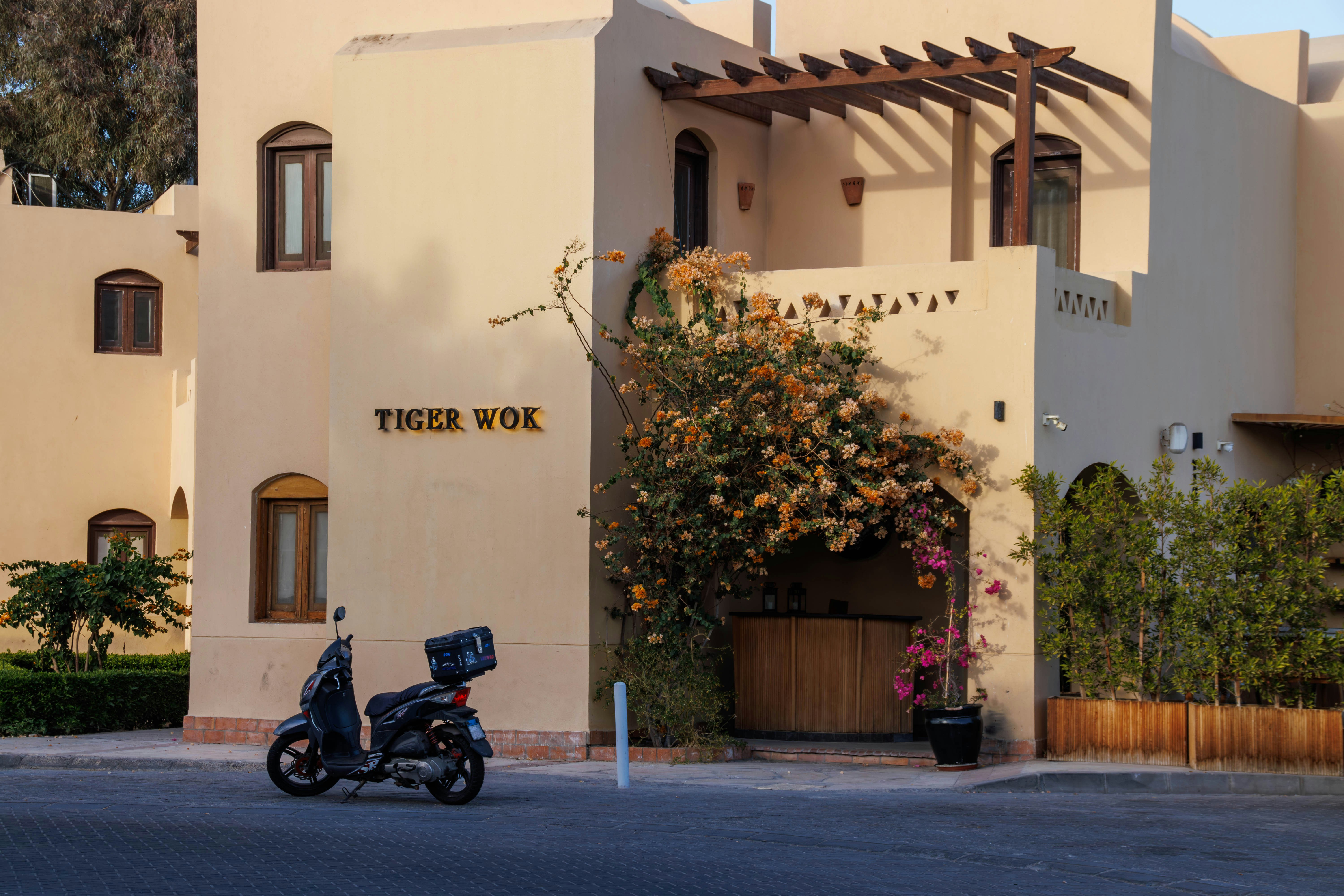 Scooter parked outside a building with flowers.