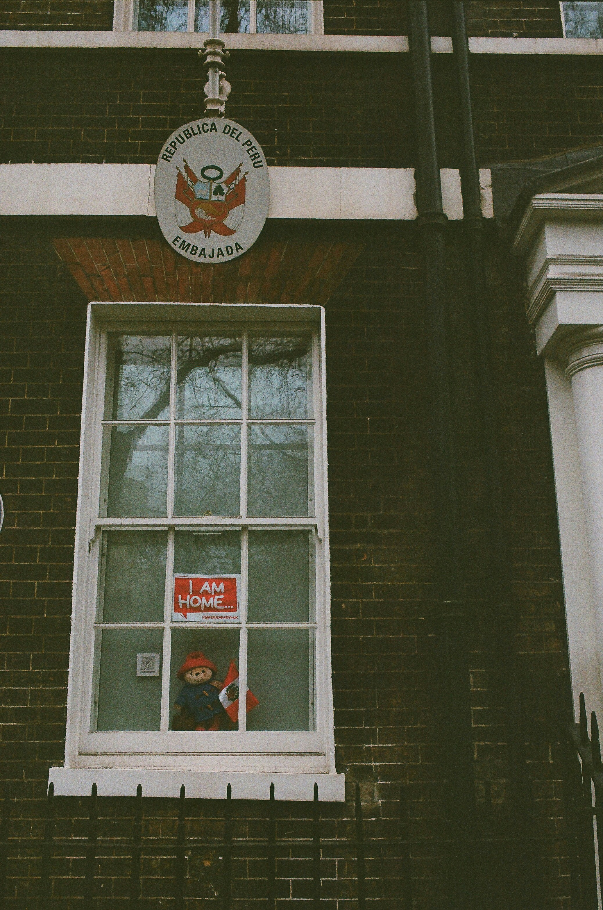 Oso de peluche en la ventana con el cartel de 'soy casa'