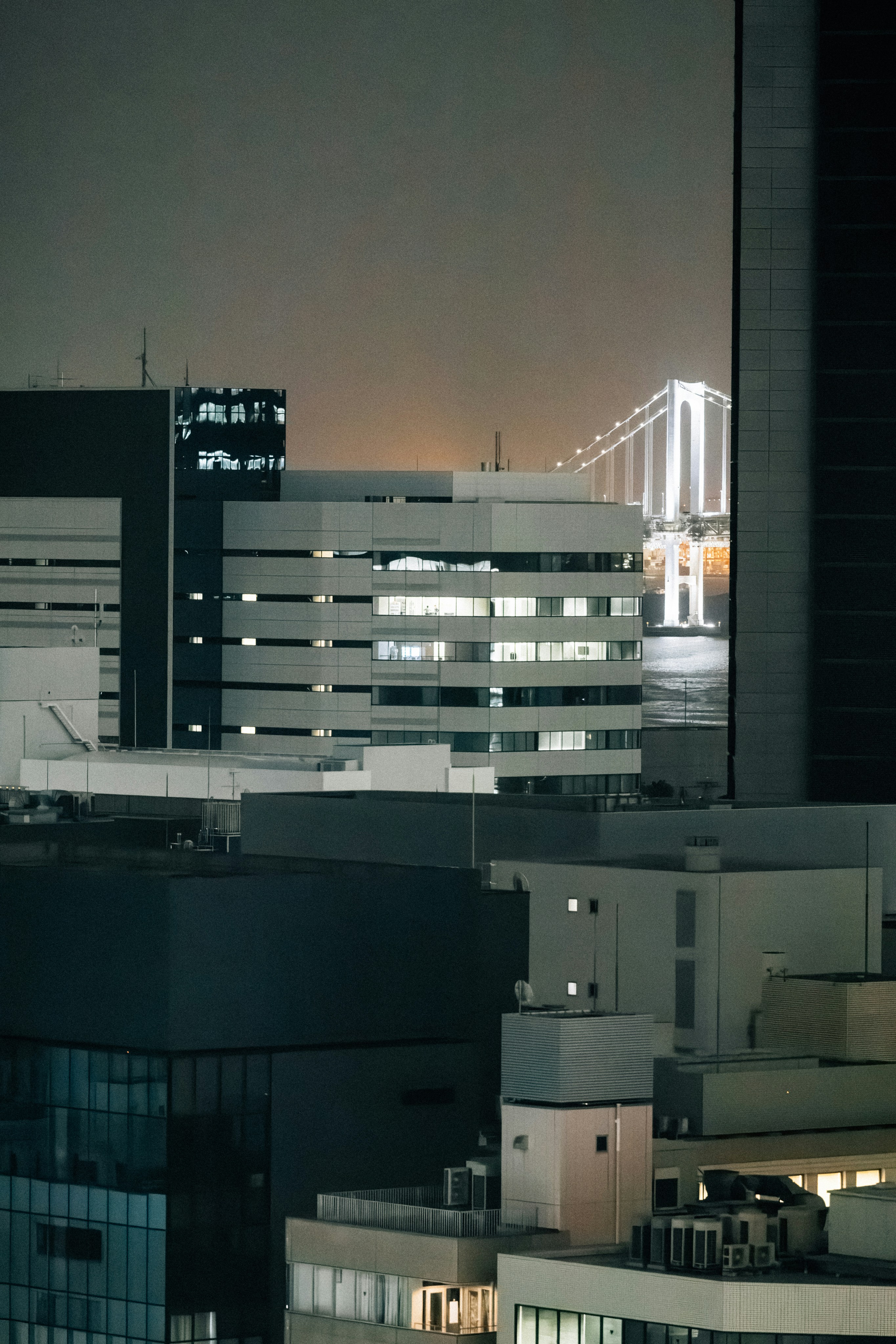 Illuminated bridge seen between city buildings at night